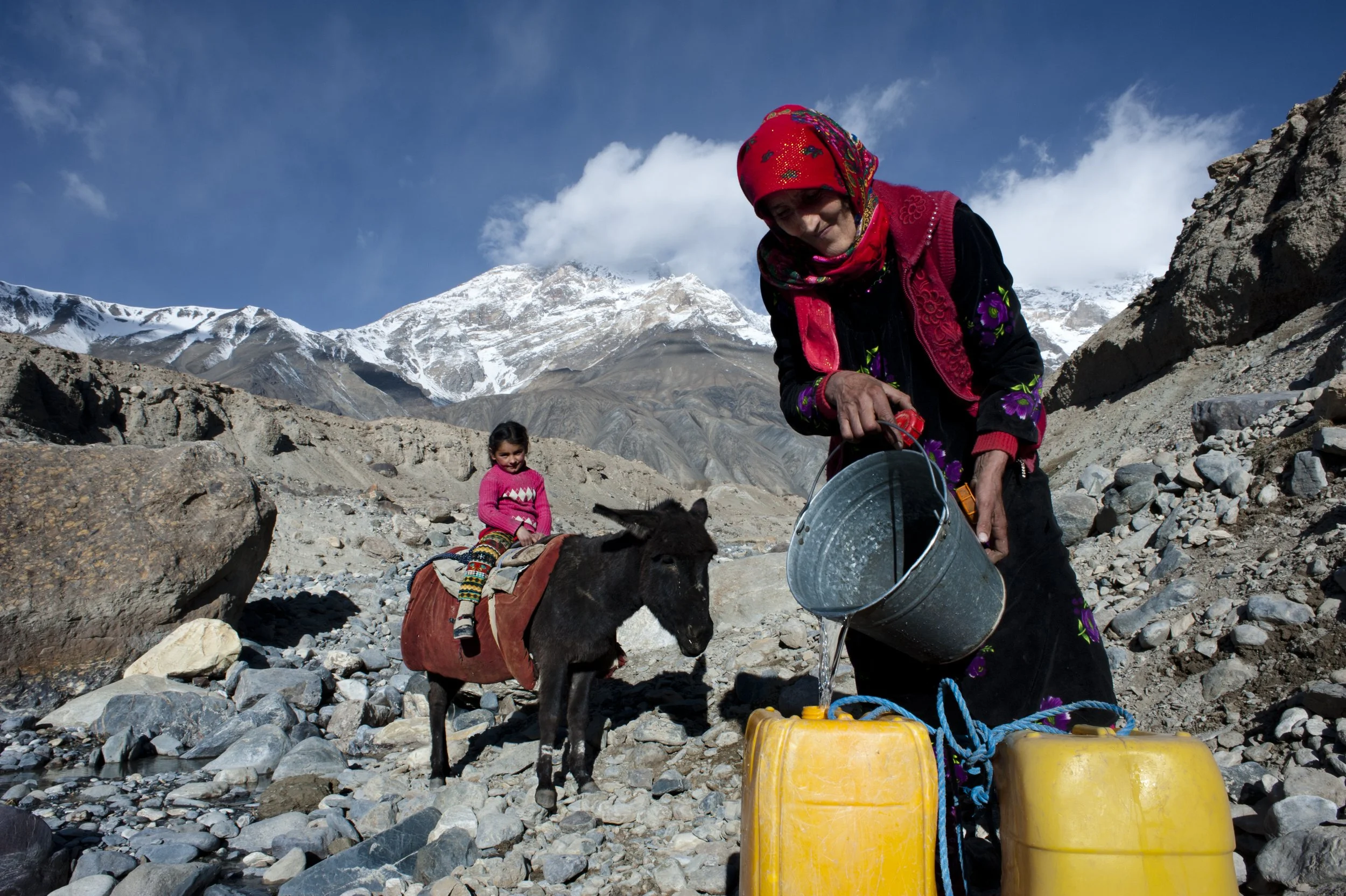 A woman takes water from a spring. The water from the spring is used for drinking and cooking. For washing and cleaning, people take water from a system of irrigation channels around the village.