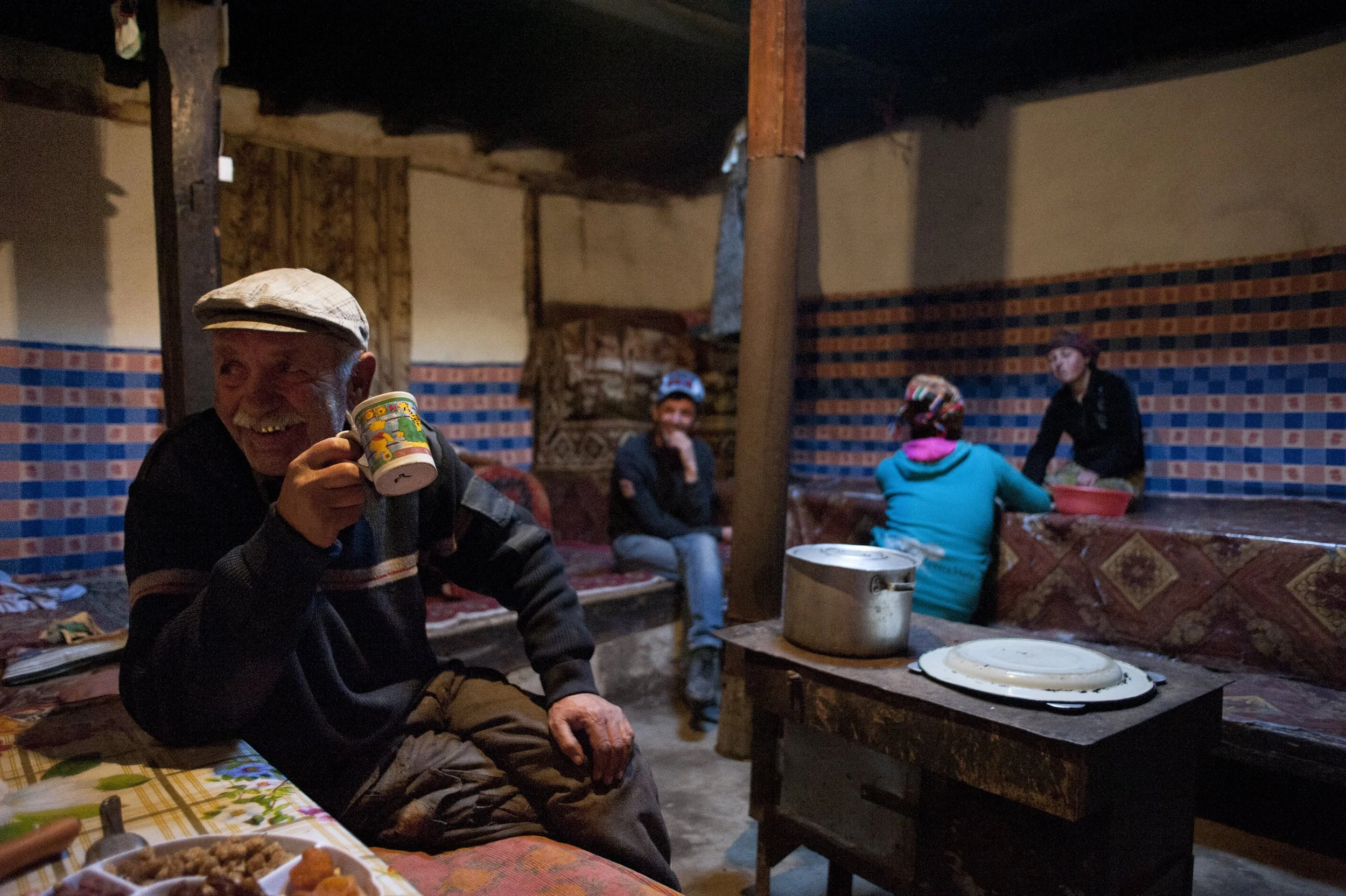Sarabdek is eating dinner. Behind, there is his son, daughter and daughter in law. In Ismaili culture women and man eat together. The head of the house usually eats with the guests from a common plate.