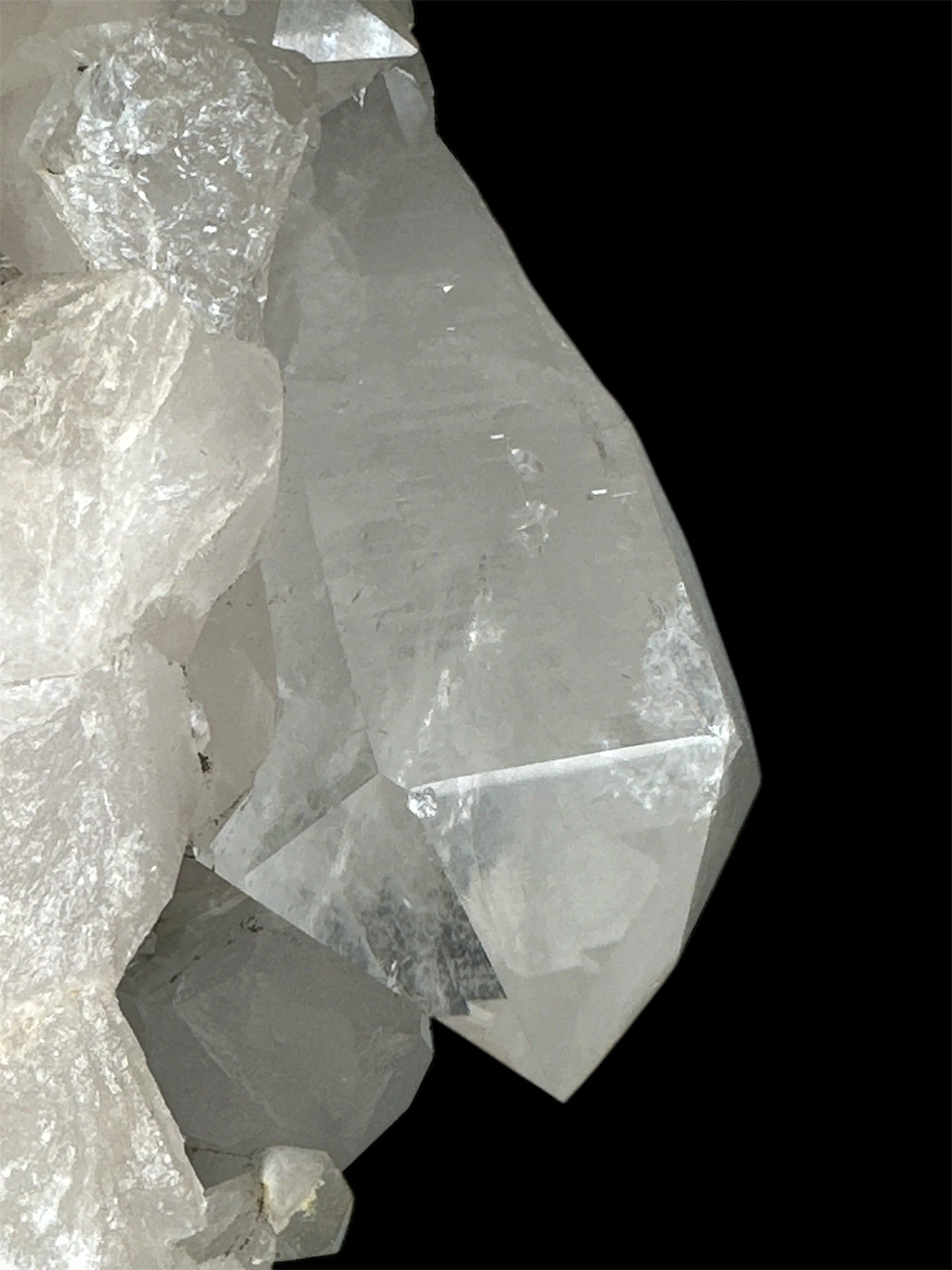 Close-up of a large, transparent, and faceted crystal or mineral specimen against a black background.
