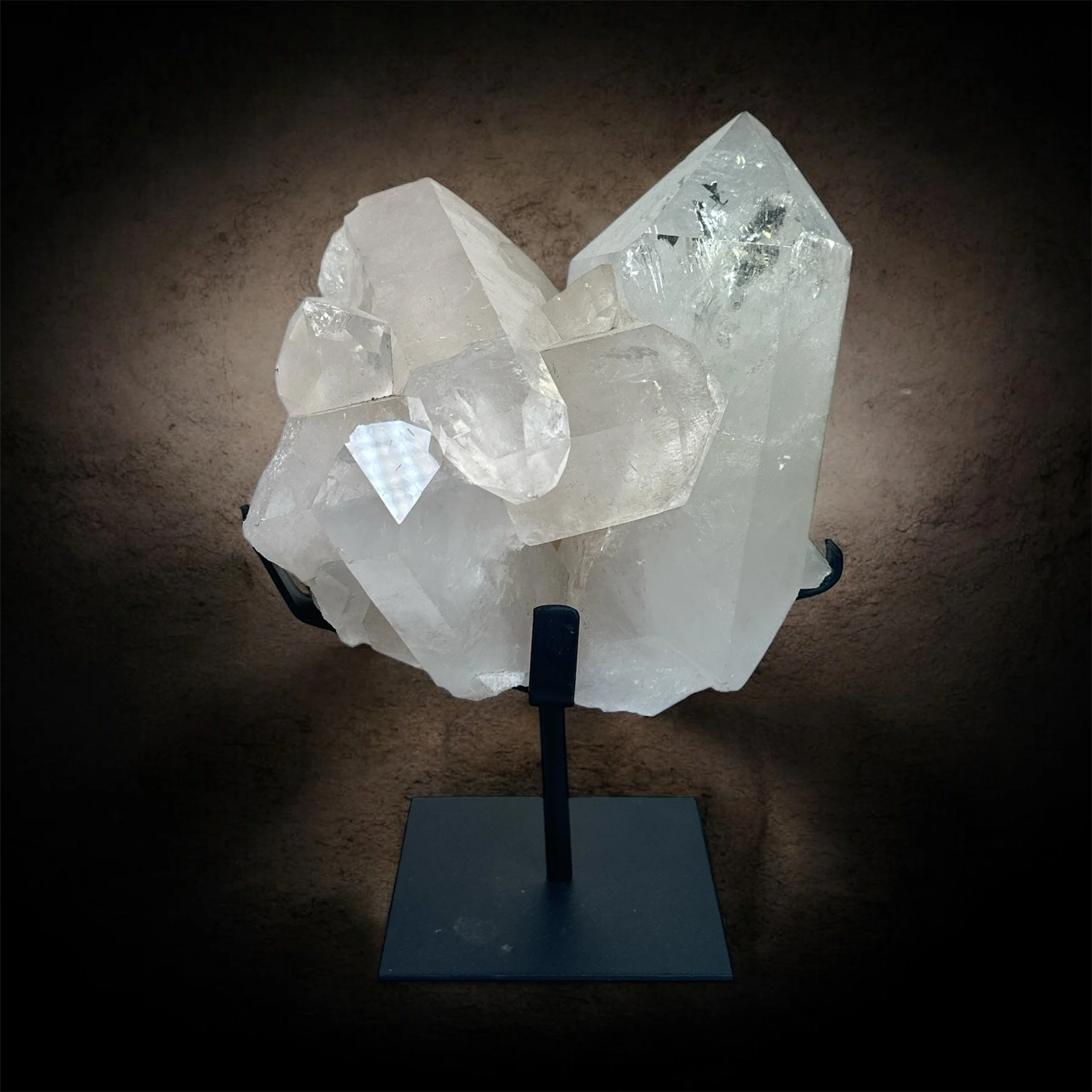 Large clear quartz crystal on a black display stand against dark background.