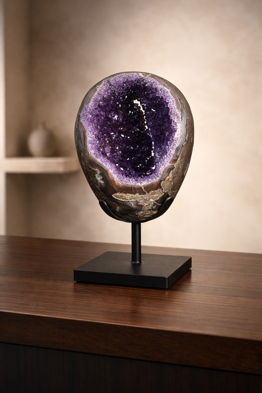 A decorative purple and brown geode on a black stand placed on a wooden table.