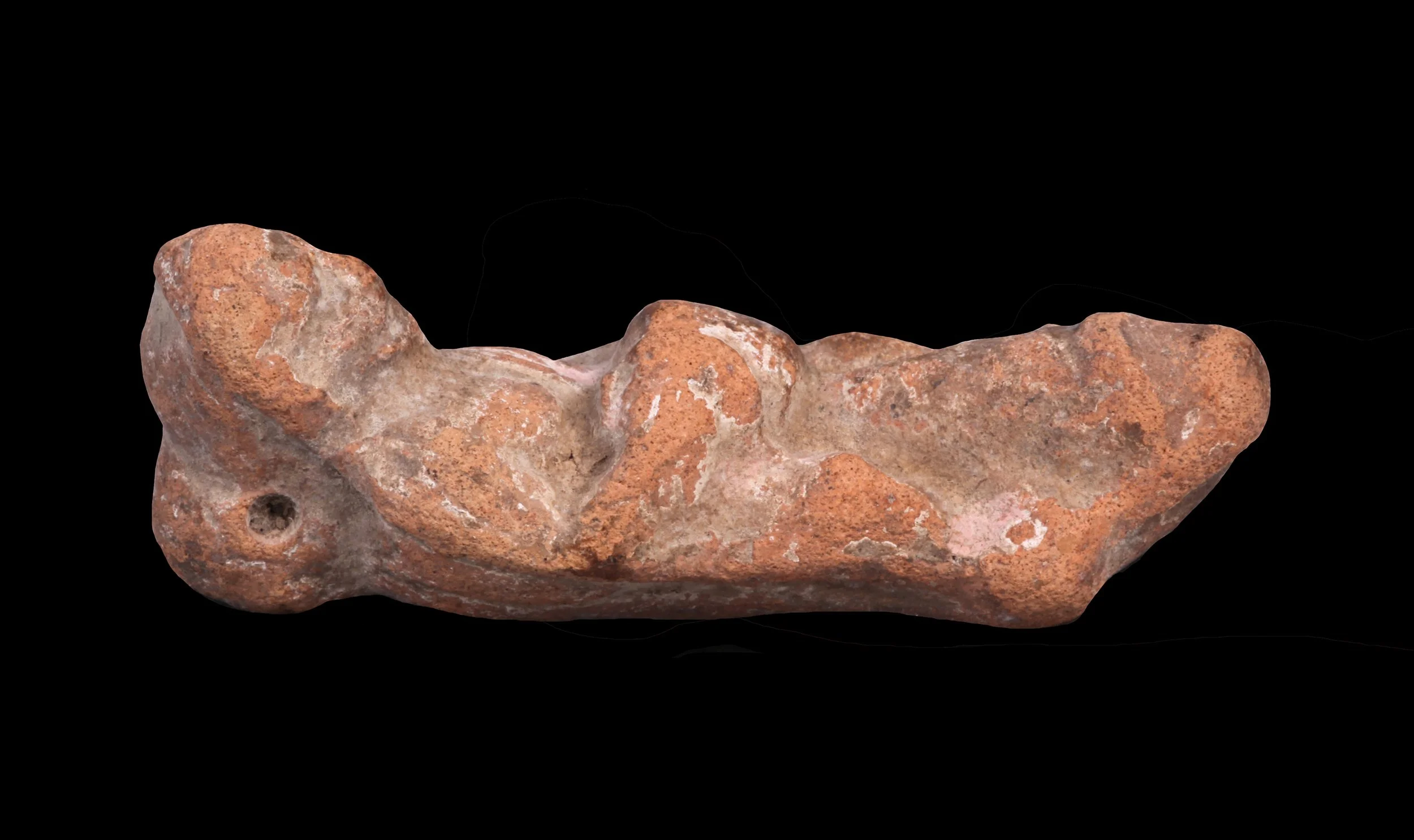 Ancient clay pipe with an irregular shape and a small hole at one end, made of reddish-brown material.