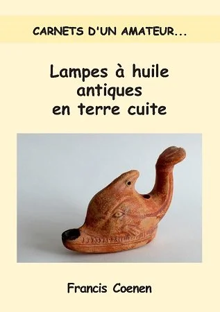 Book cover titled 'Carnets d'un amateur... Lampes à huile antiques en terre cuite' featuring a photo of an antique clay oil lamp shaped like a dog's head and an author named Francis Coenen.