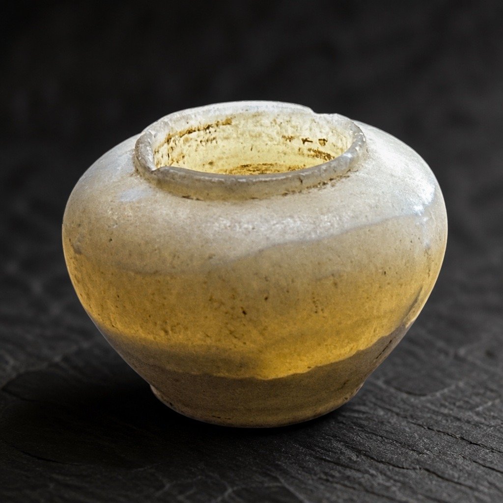 Close-up of an ancient pottery vessel on a dark wooden surface.