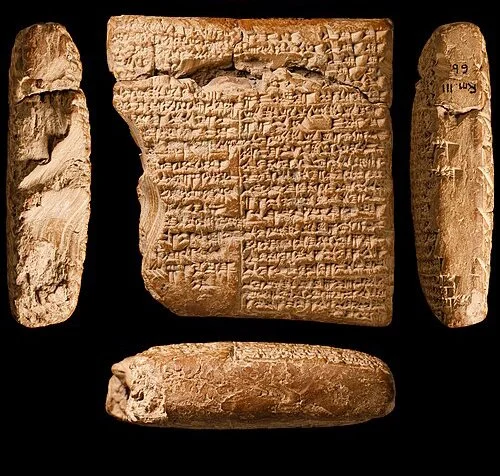 Ancient clay tablet with cuneiform inscriptions, flanked by four clay fragments with cuneiform writing.