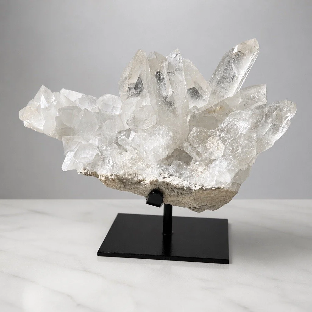 A clear quartz crystal cluster displayed on a black stand.
