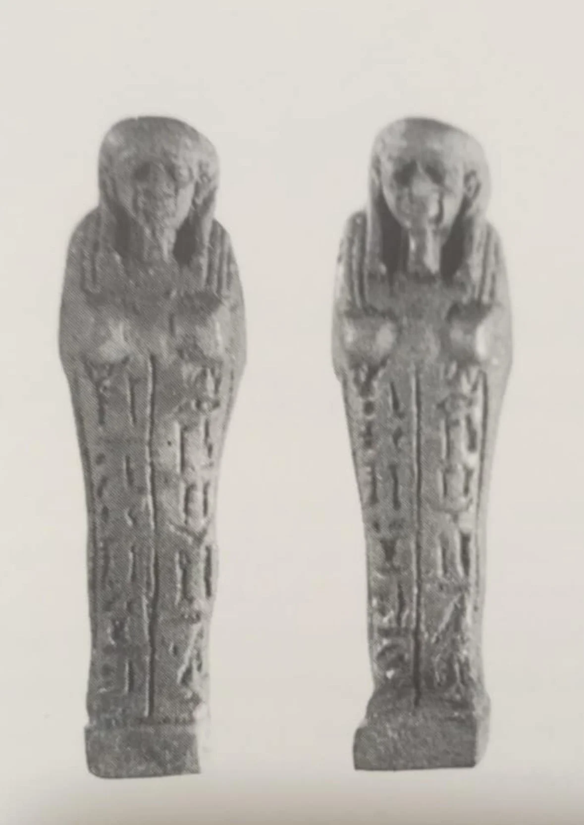 Two ancient Egyptian shabti figurines with detailed carved hieroglyphs on their bodies, standing side by side.