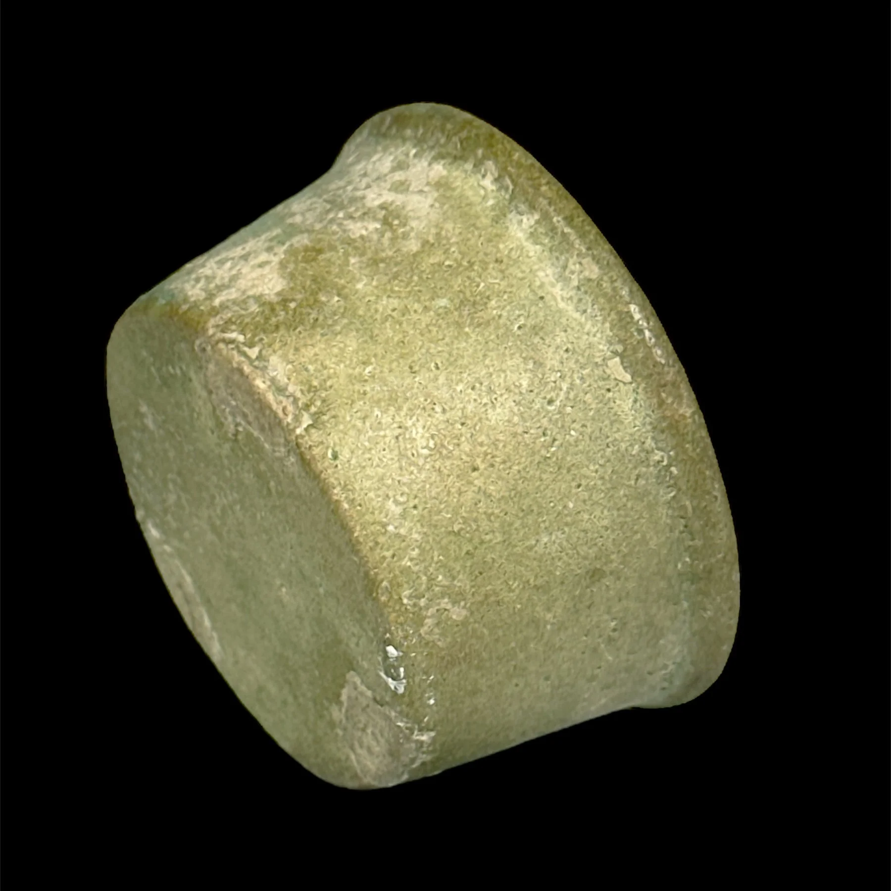 Close-up of a small, rough, beige-colored cube on a black background.
