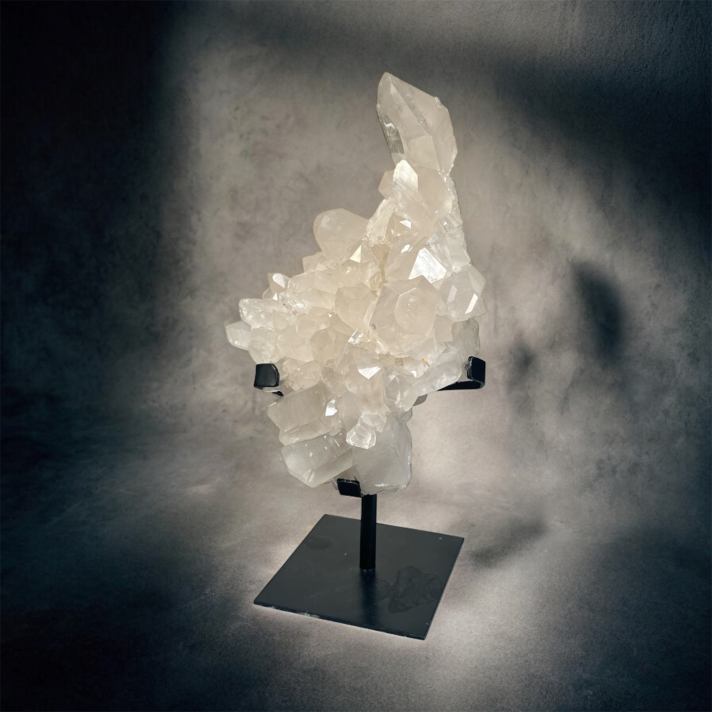 White quartz crystal display mounted on a black stand against a dark background.