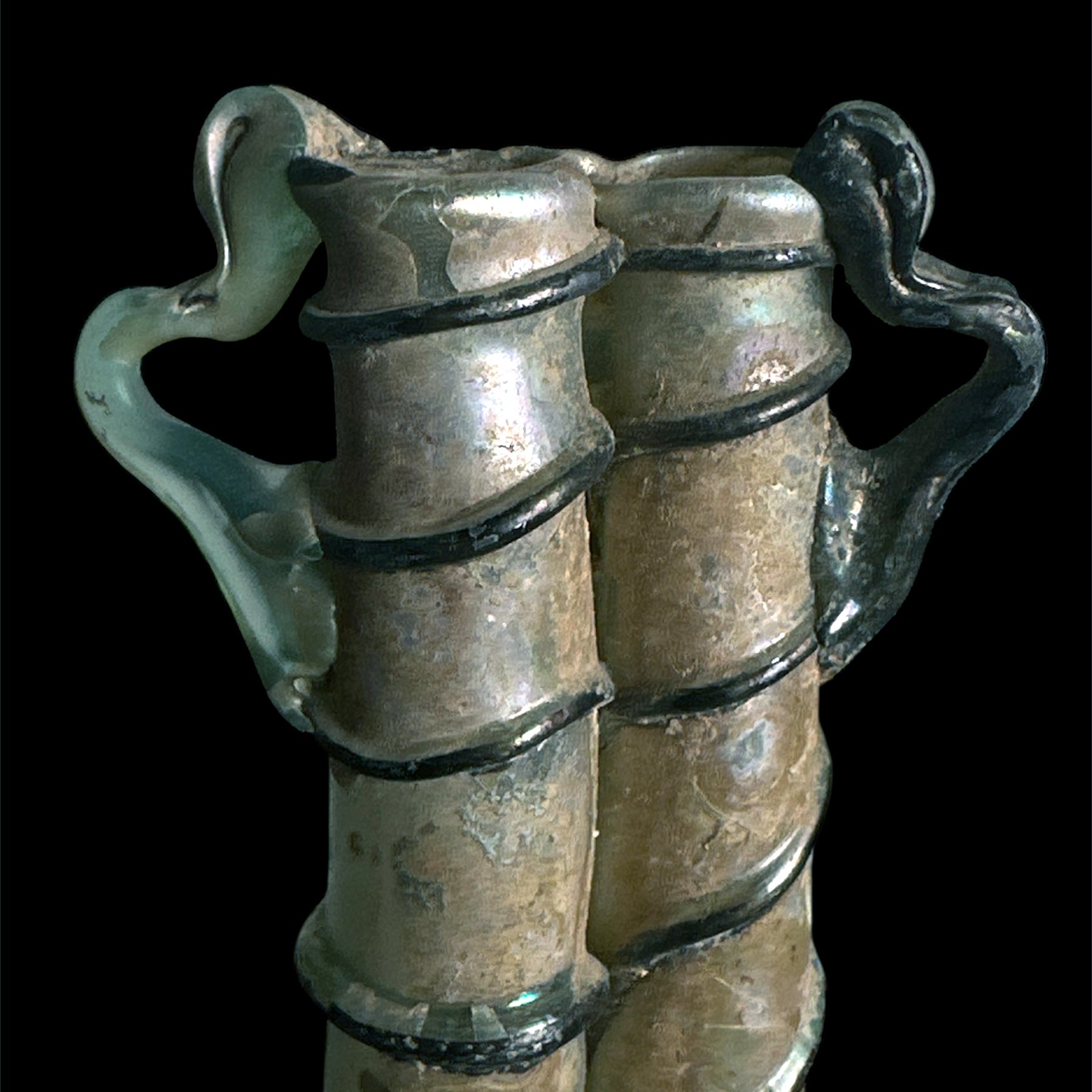 Decorative brass or bronze figurine resembling a pair of human legs with black accents, mounted on a black background.