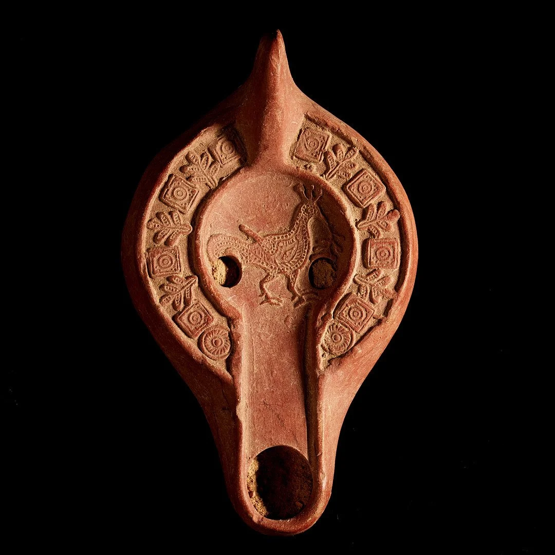 Ancient terracotta relic with a carved bird in the center and geometric patterns around it, set against a black background.