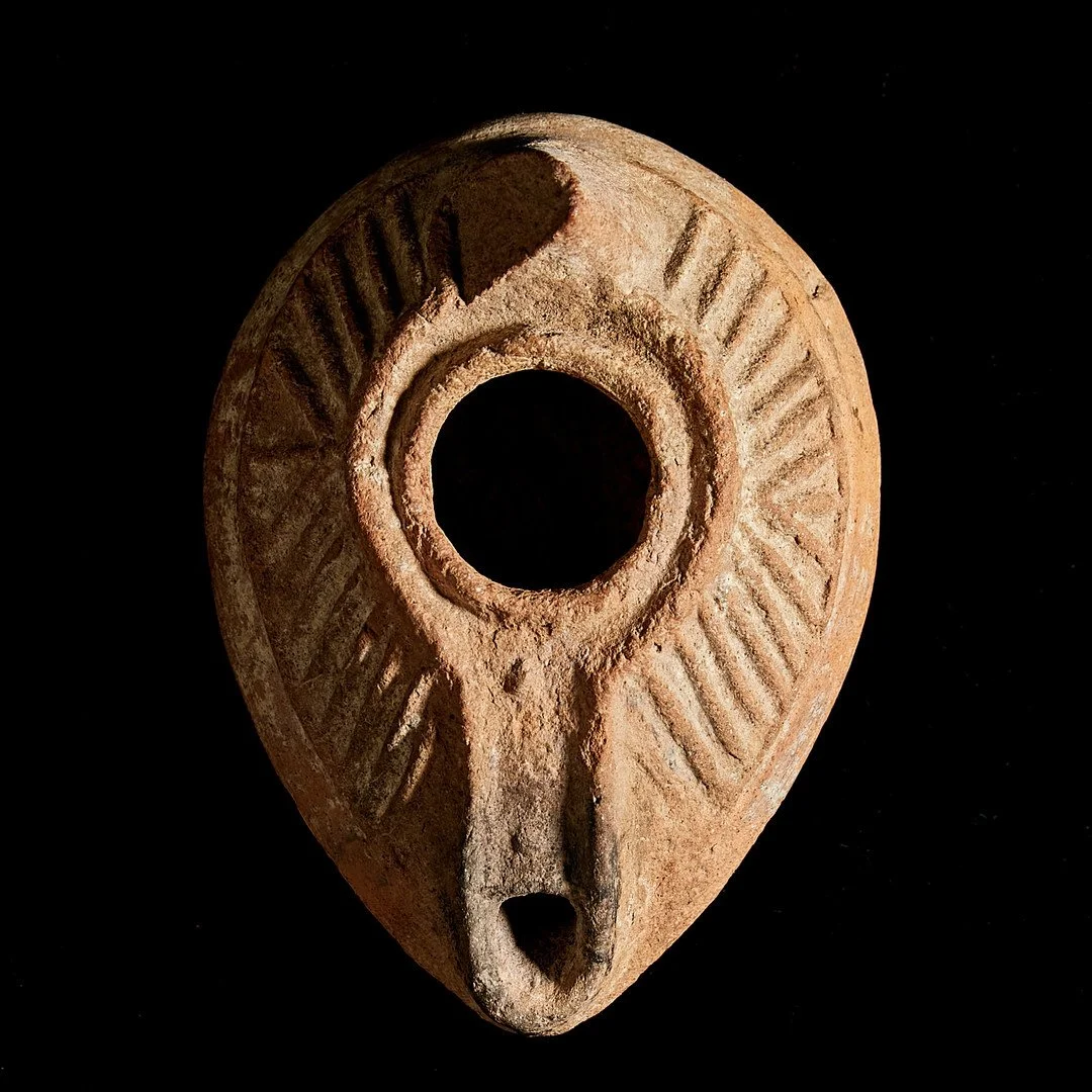 Ancient oil lamp with geometric patterns, on a black background.