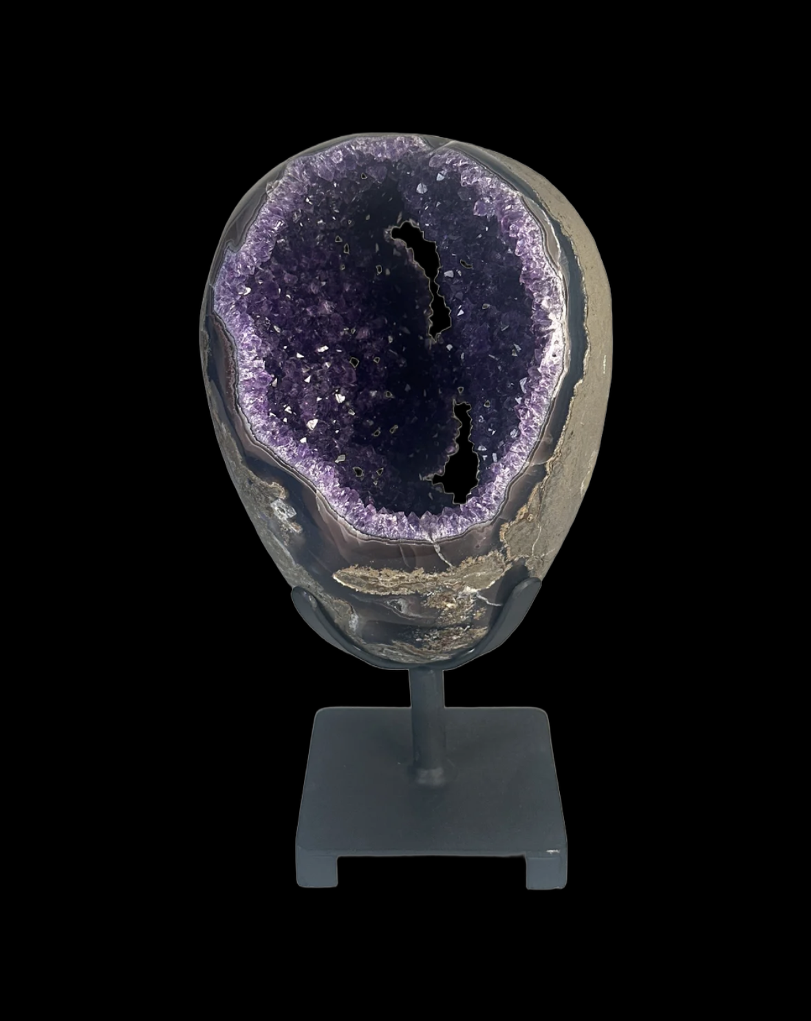 A large amethyst geode mounted on a stand, showing purple crystalline interior with sparkling crystals and a rough outer edge, against a black background.