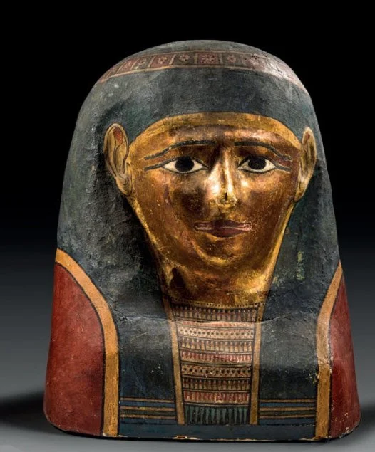 Ancient Egyptian painted coffin with a gold face and black hair, featuring detailed jewelry and decoration.