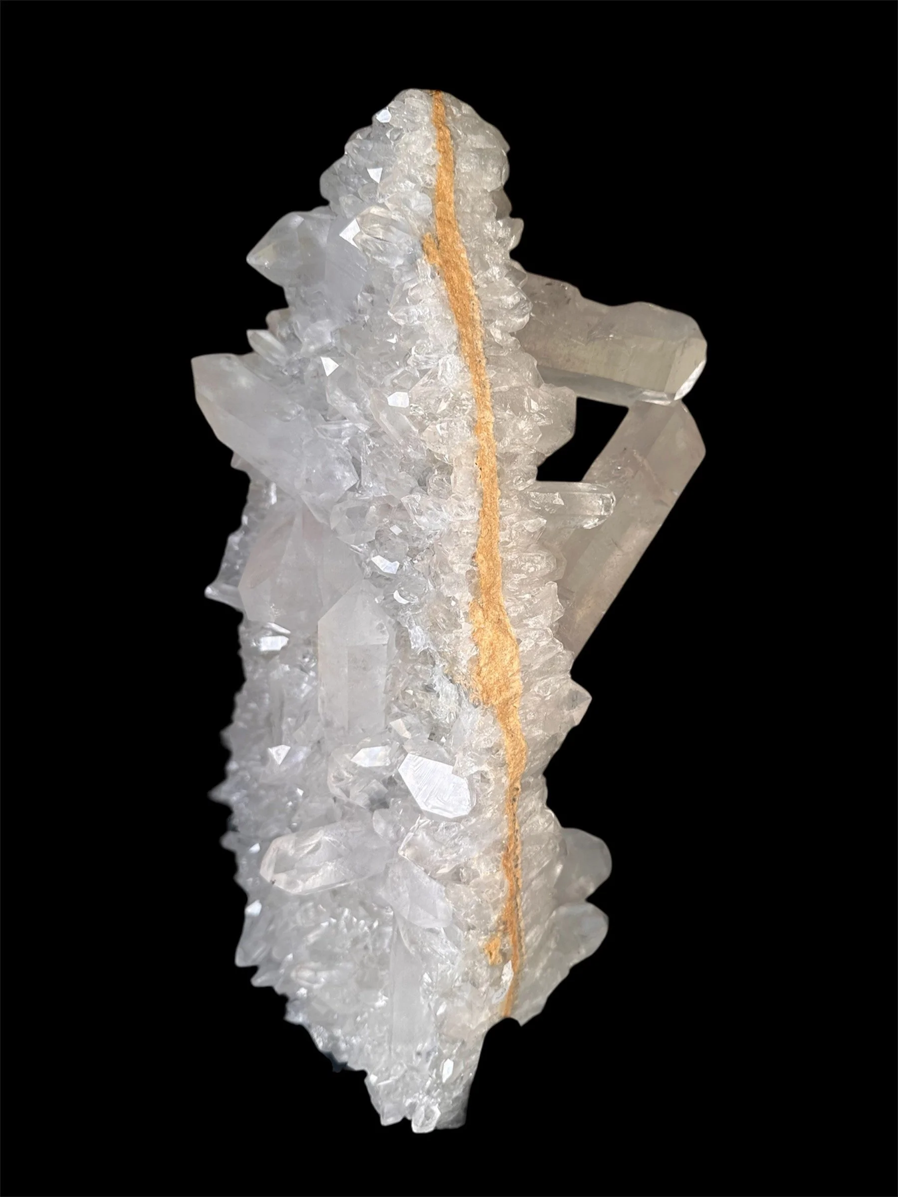 A large, clear quartz crystal with a brown streak running through the center, set against a black background.