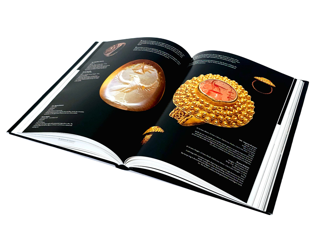 Open book displaying images and information about three gold jewelry items, including rings and a watch with a red face, on a black background.