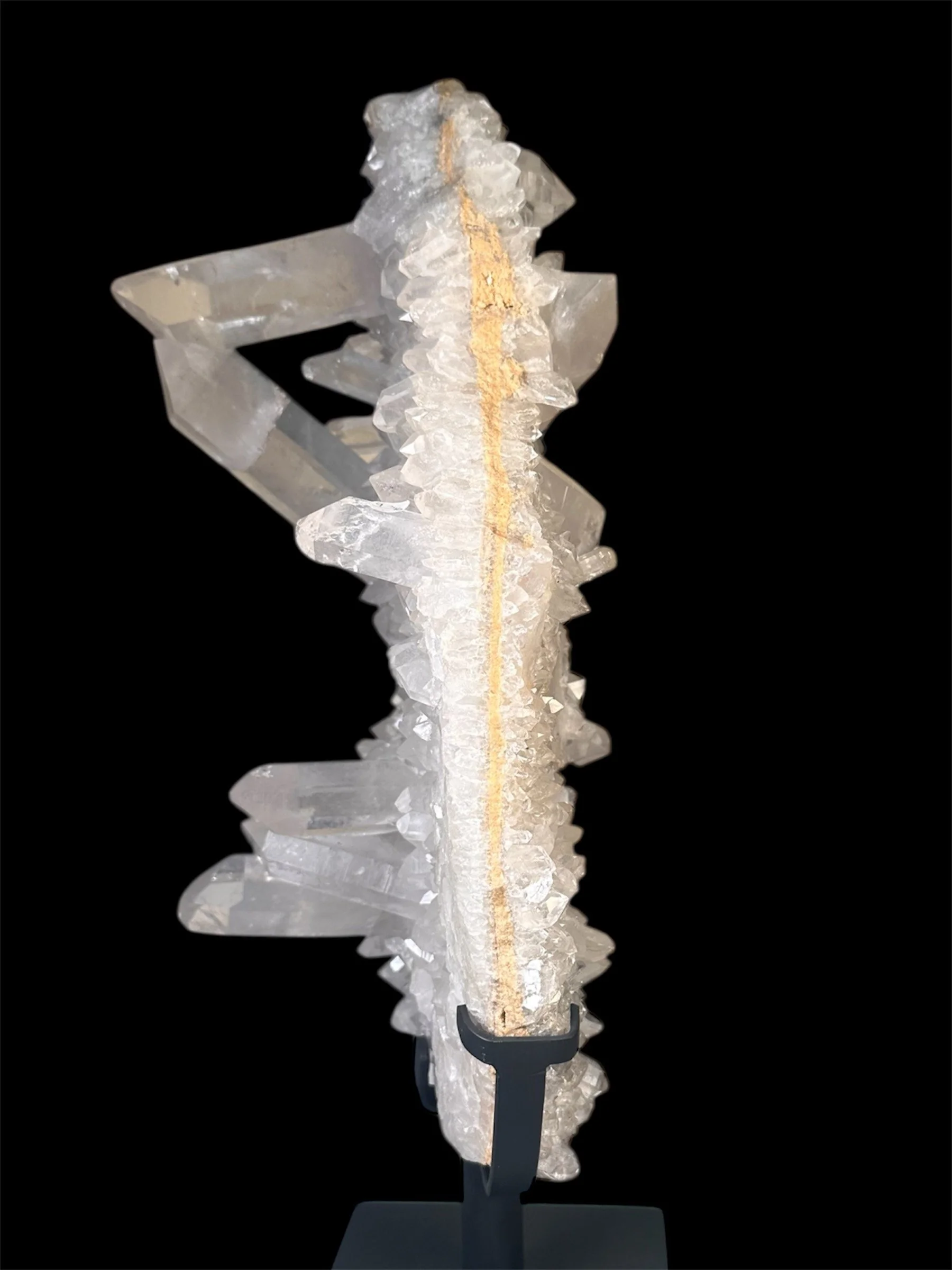 A large, clear quartz crystal specimen displayed on a stand against a black background.