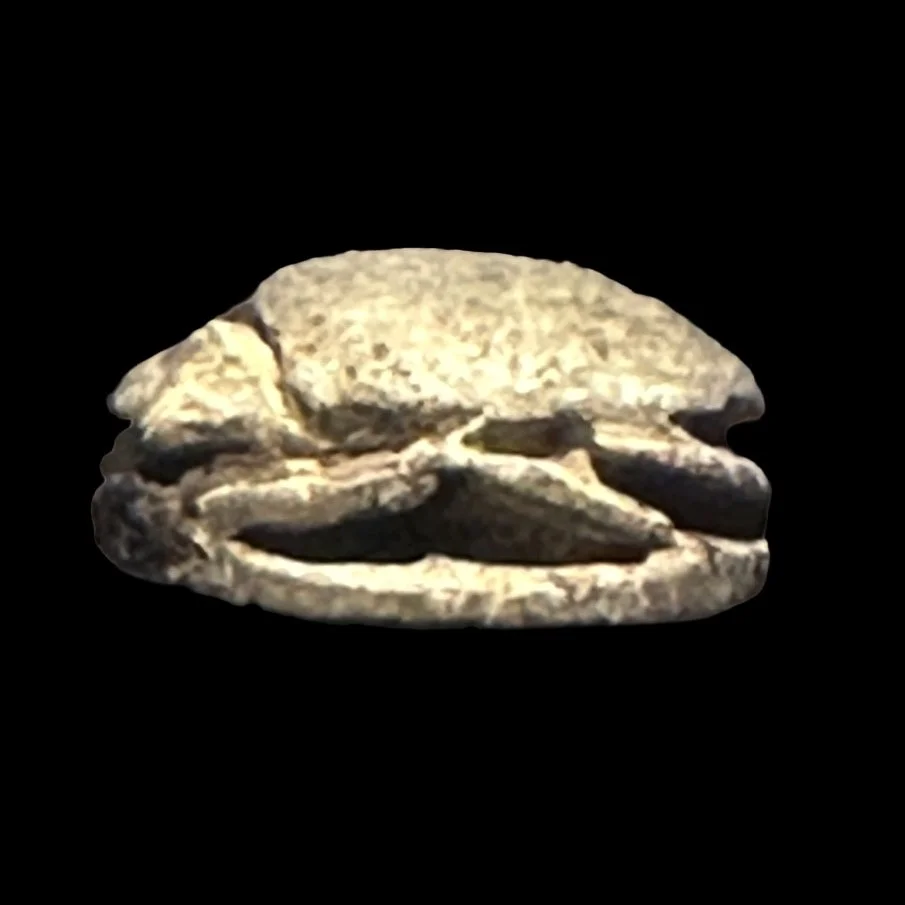 Ancient stone artifact resembling a stylized face or mask, set against a black background.
