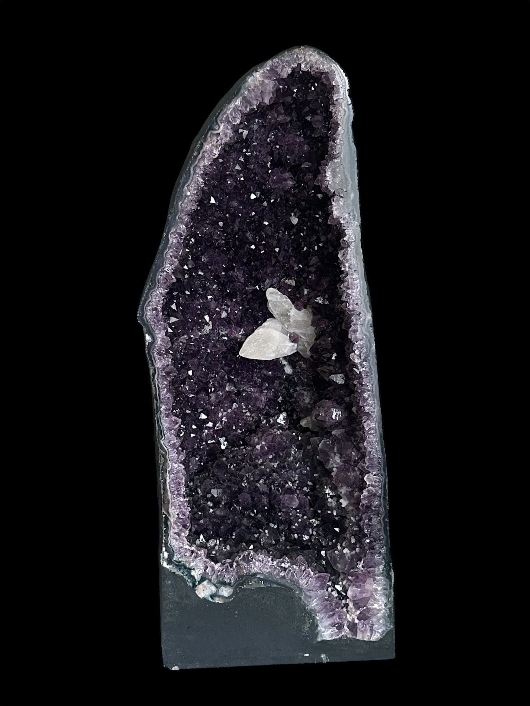 A purple geode with a crystal interior and a white gift bow inside, set against a black background.