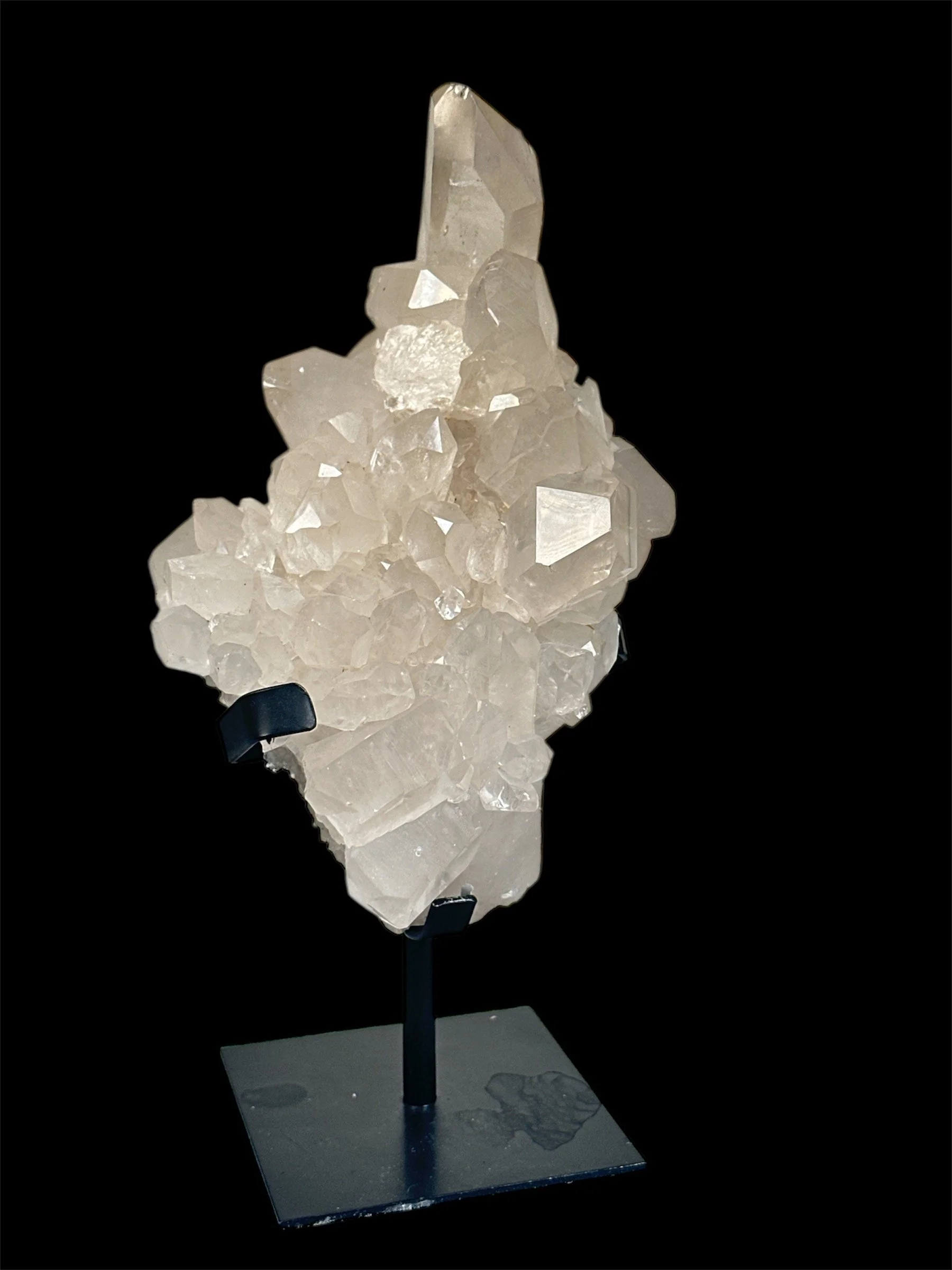 White crystalline mineral specimen displayed on a black stand against a black background.