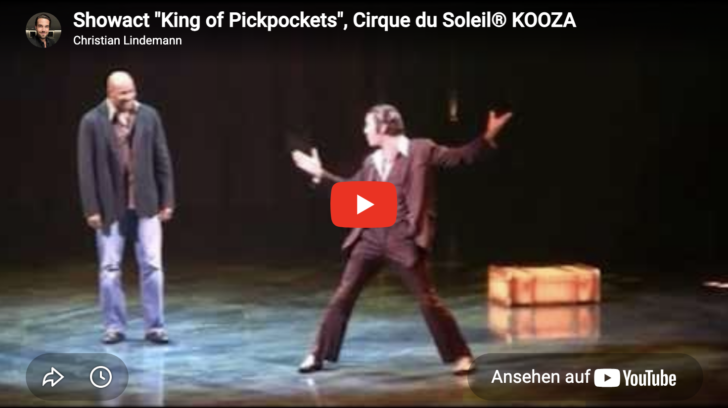 Zwei Männer auf einer Bühne, einer steht schweigend, der andere gestikulierend, bei einer Theateraufführung des Cirque du Soleil, Showakt 'King of Pickpockets'.