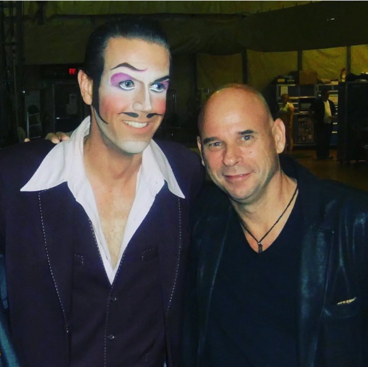 Zwei Männer, einer mit einem aufwändigen Piratenkostüm und Schminke, der andere trägt eine Lederjacke, zusammen auf einer Party.