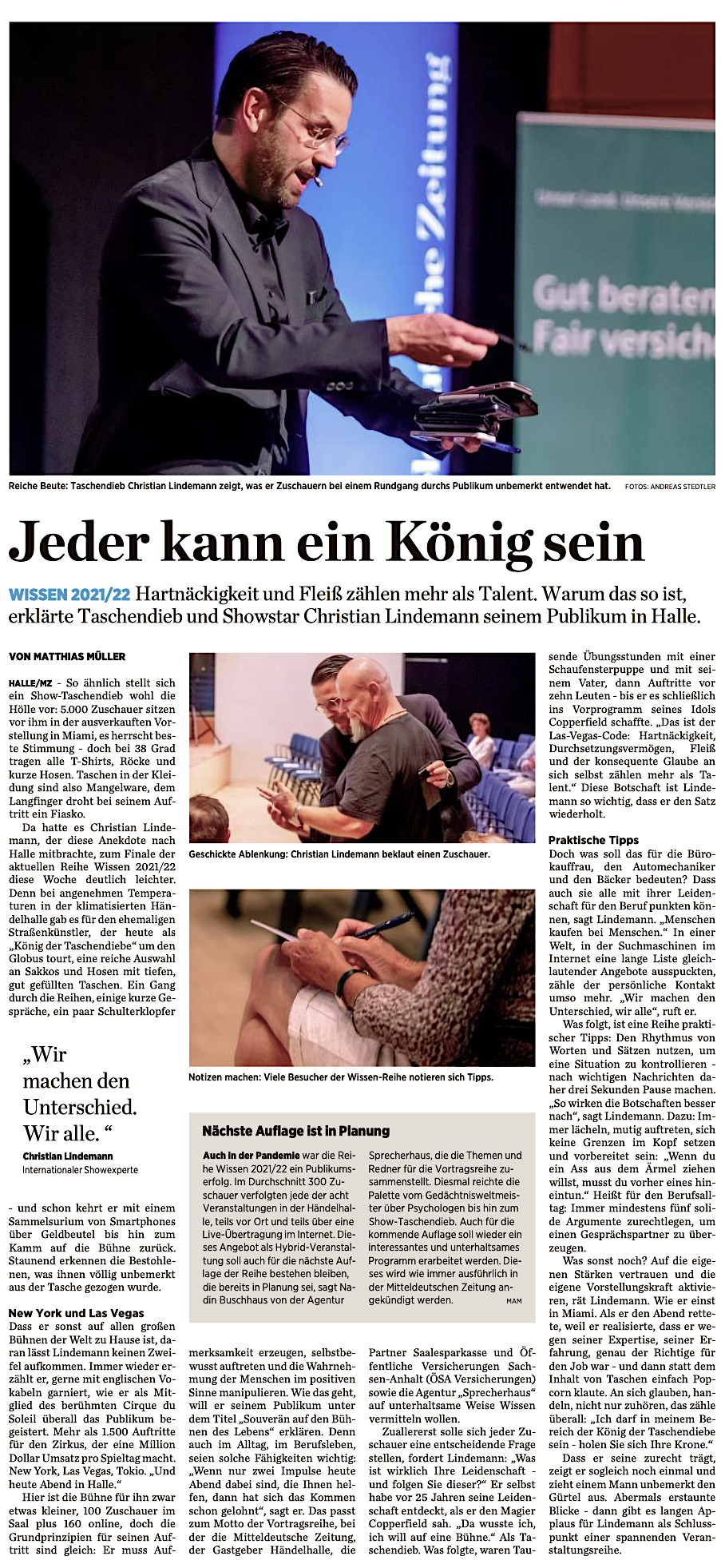 Ein Mann in dunklem Sakko zeigt während eines Vortrags auf eine kleine Tasche in seiner Hand, im Hintergrund ein Publikum und eine grüne Werbung.