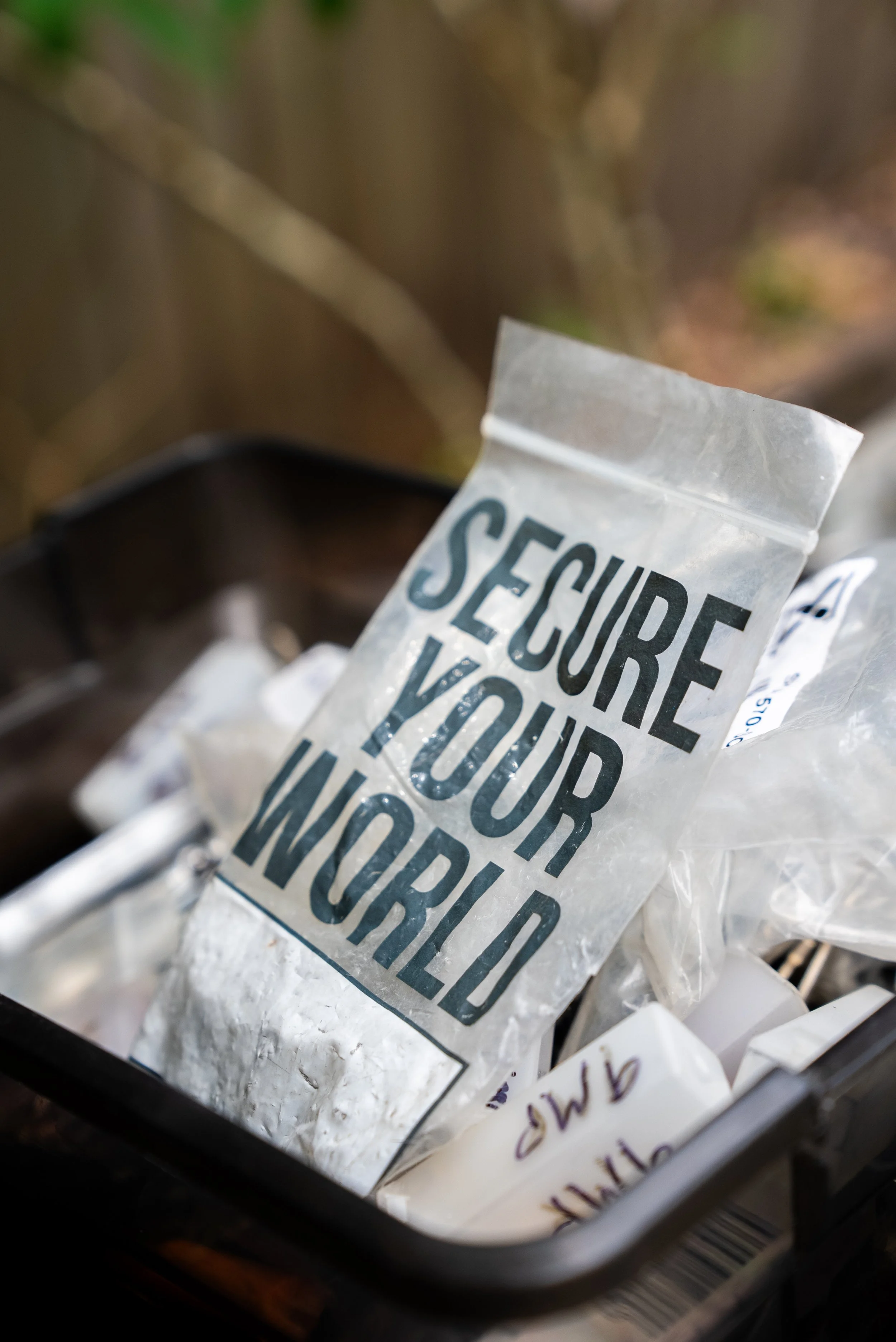 Close-up of a plastic bag with a label that reads 'Secure Your Workshop,' placed inside a box with other bags and items.