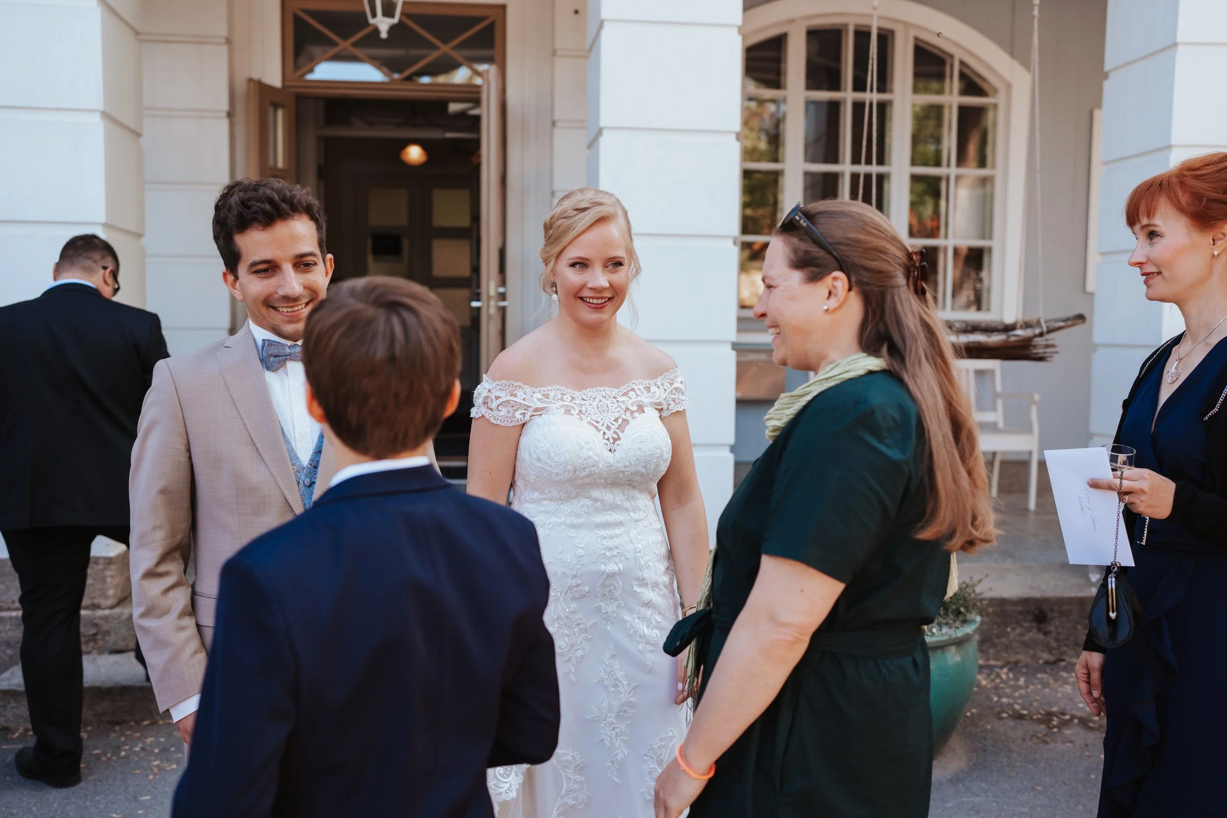 Bride and groom talking to guests at outdoor wedding reception.