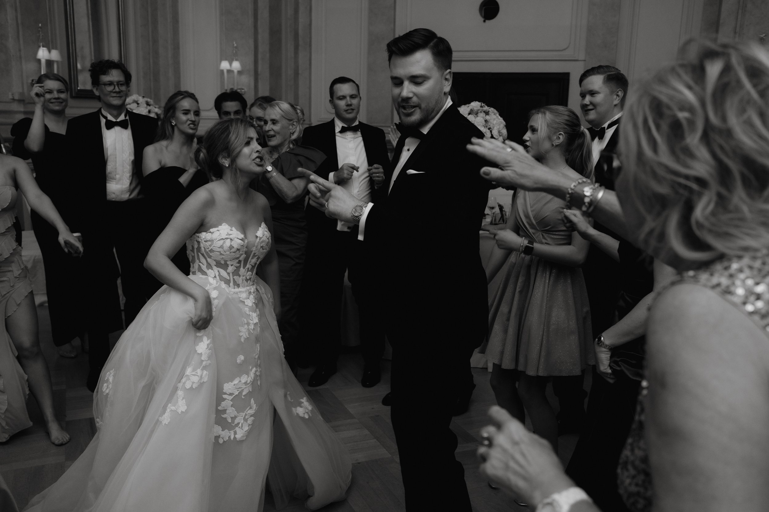 Bride and groom dancing surrounded by guests at a wedding reception.