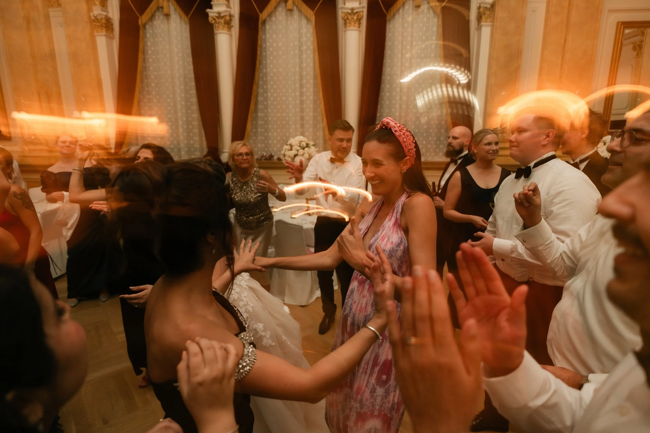 People dancing and celebrating at an indoor event, with dim lighting and motion blur effects.