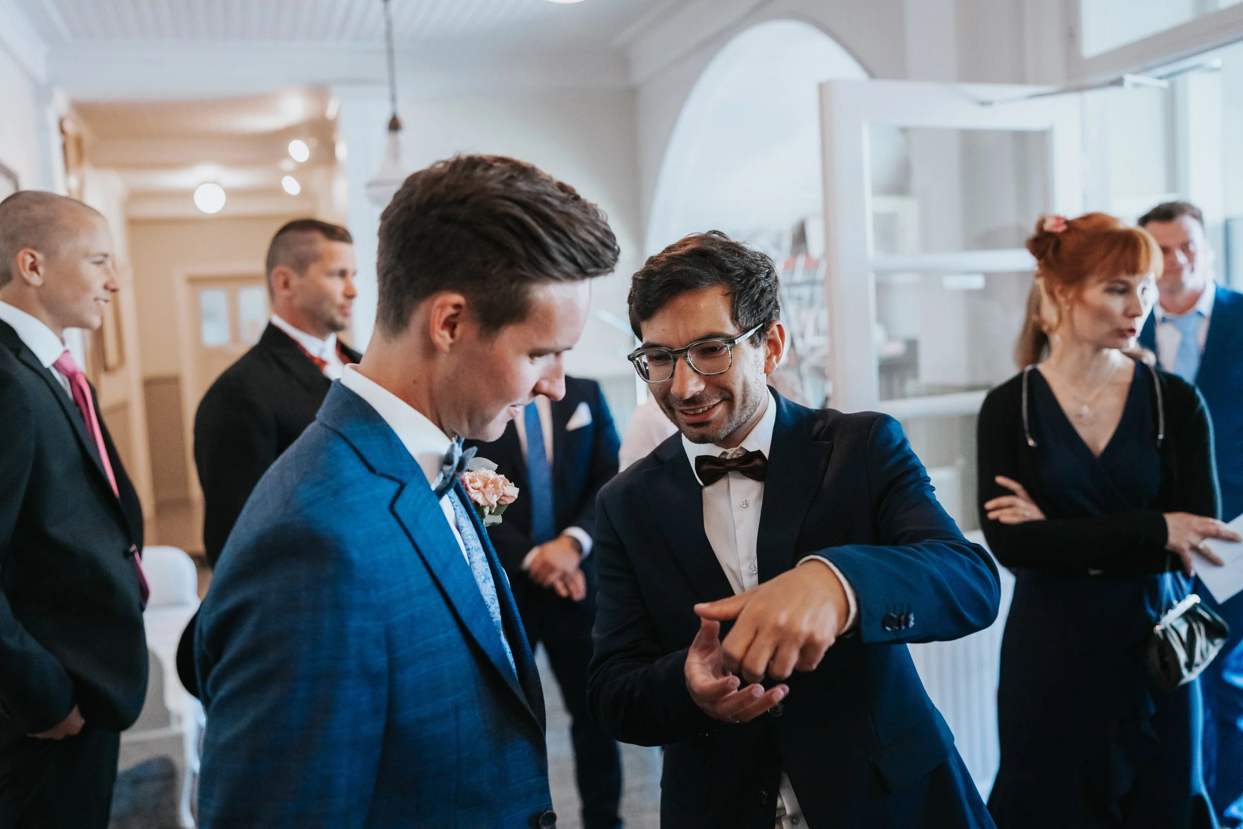 Group of people dressed in formal attire, socializing indoors at an event.