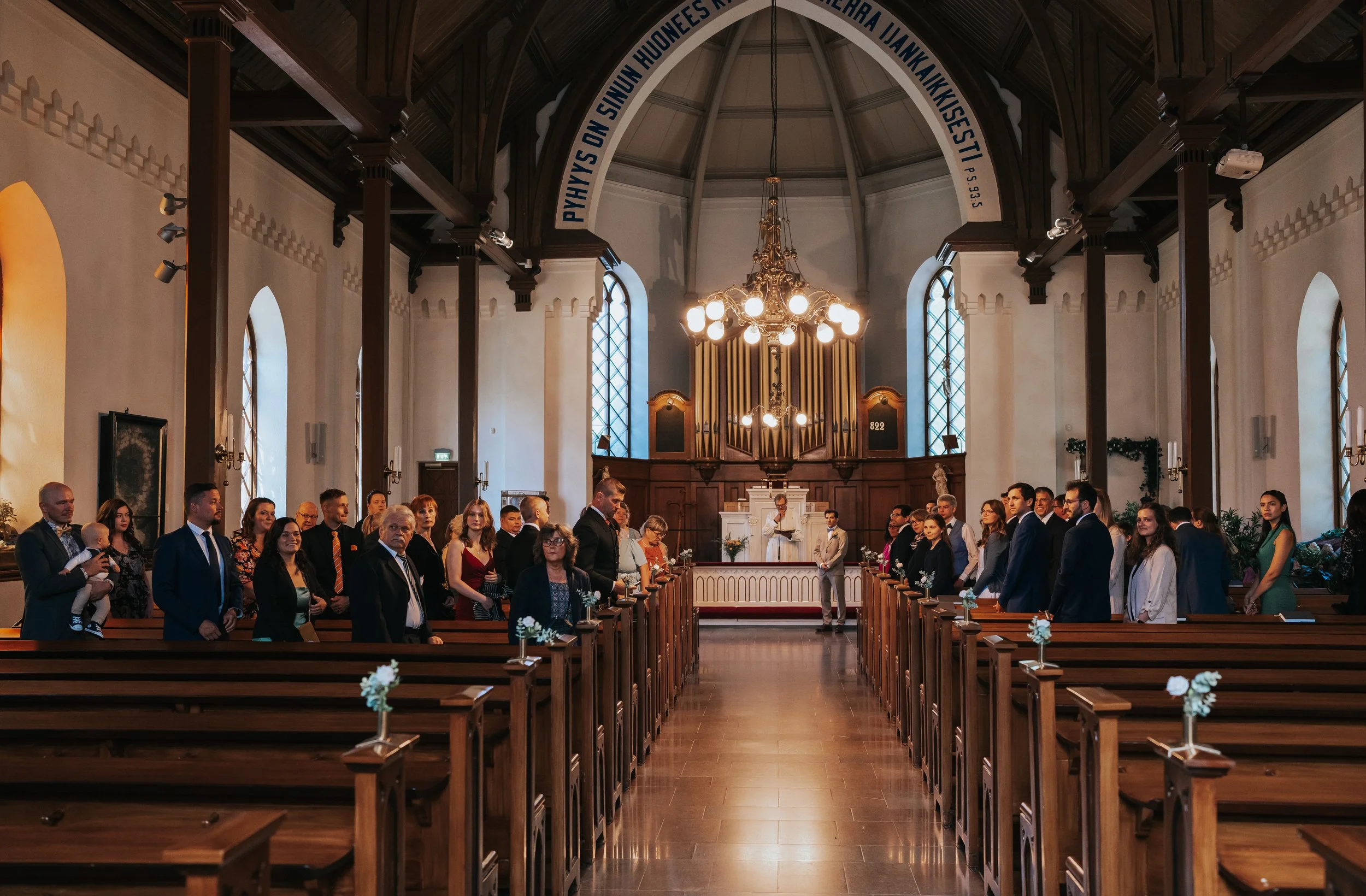 People seated in a church, facing the altar, during a ceremony.