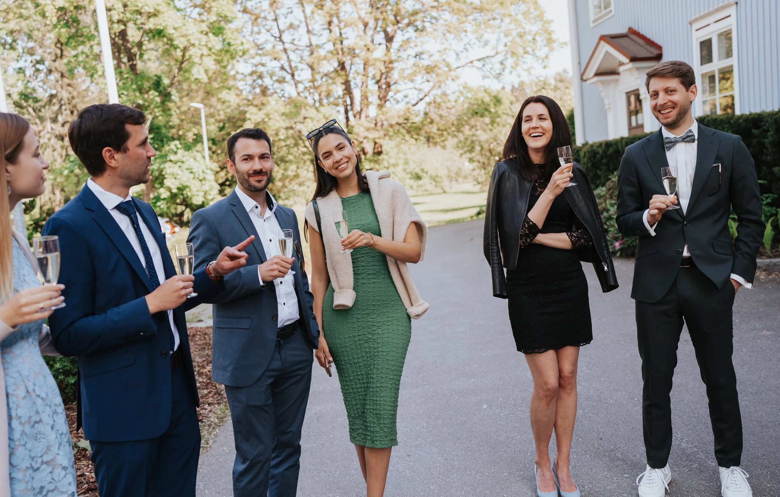 Group of people in formal attire holding champagne glasses outdoors