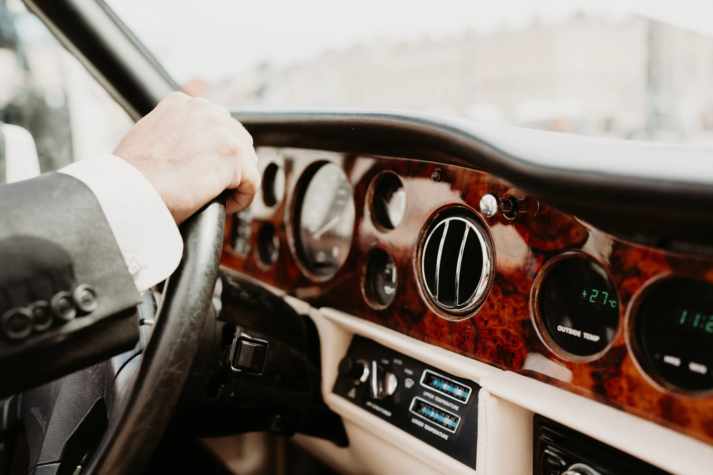 Close-up of vintage car dashboard with wood trim and analog dials.