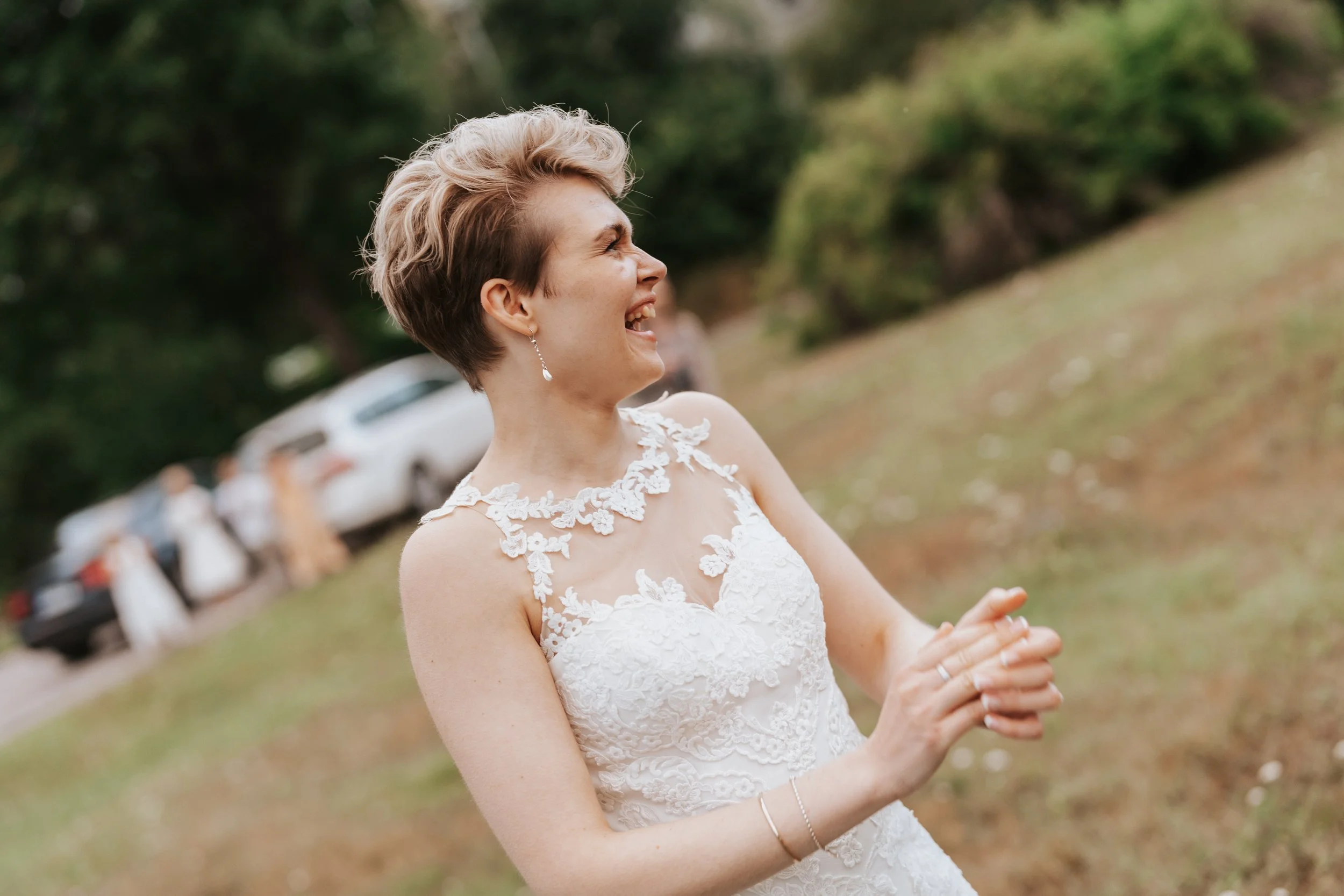 Bride in lace wedding dress outdoors, smiling