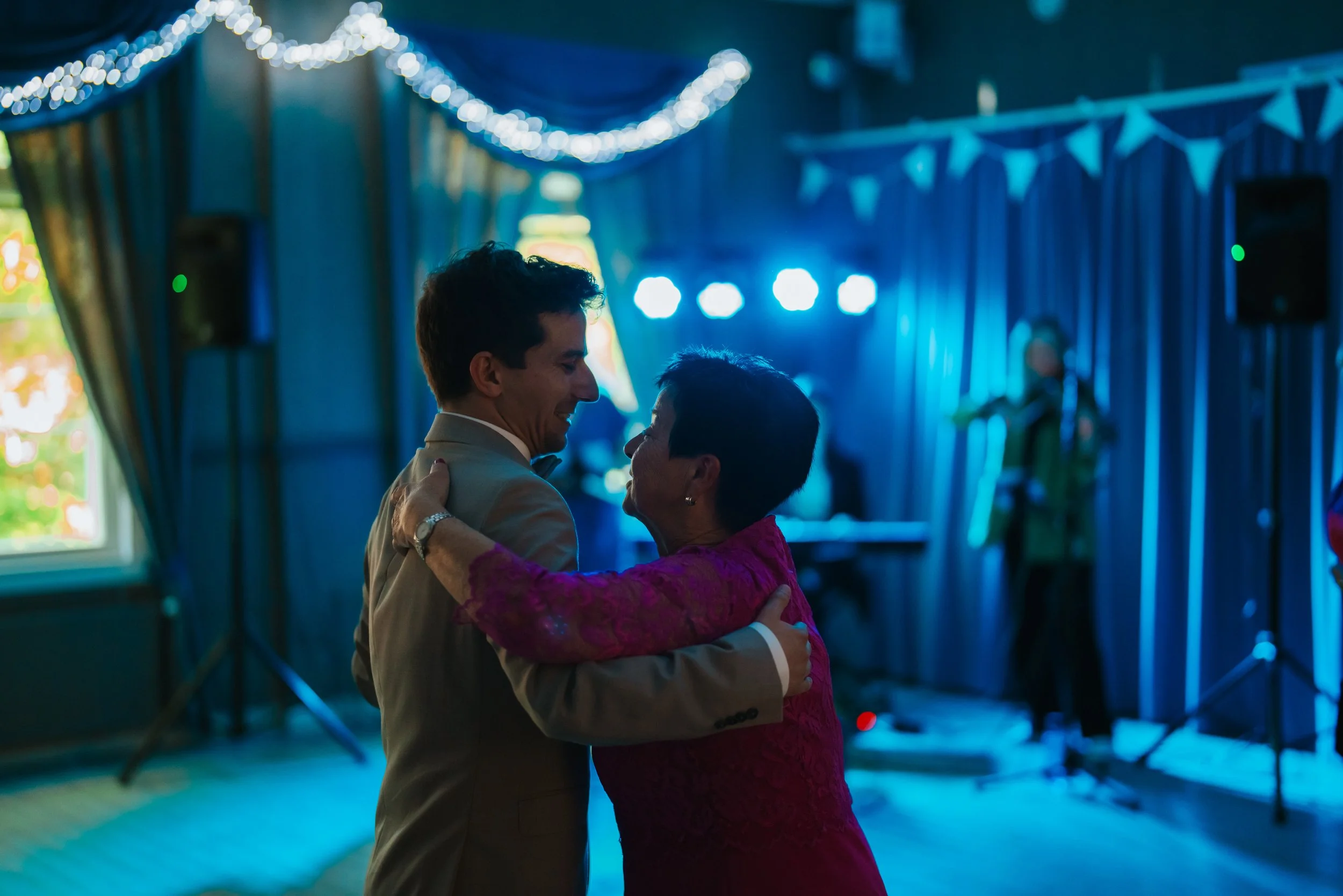 A couple dancing at an event with blue lighting and decorations.