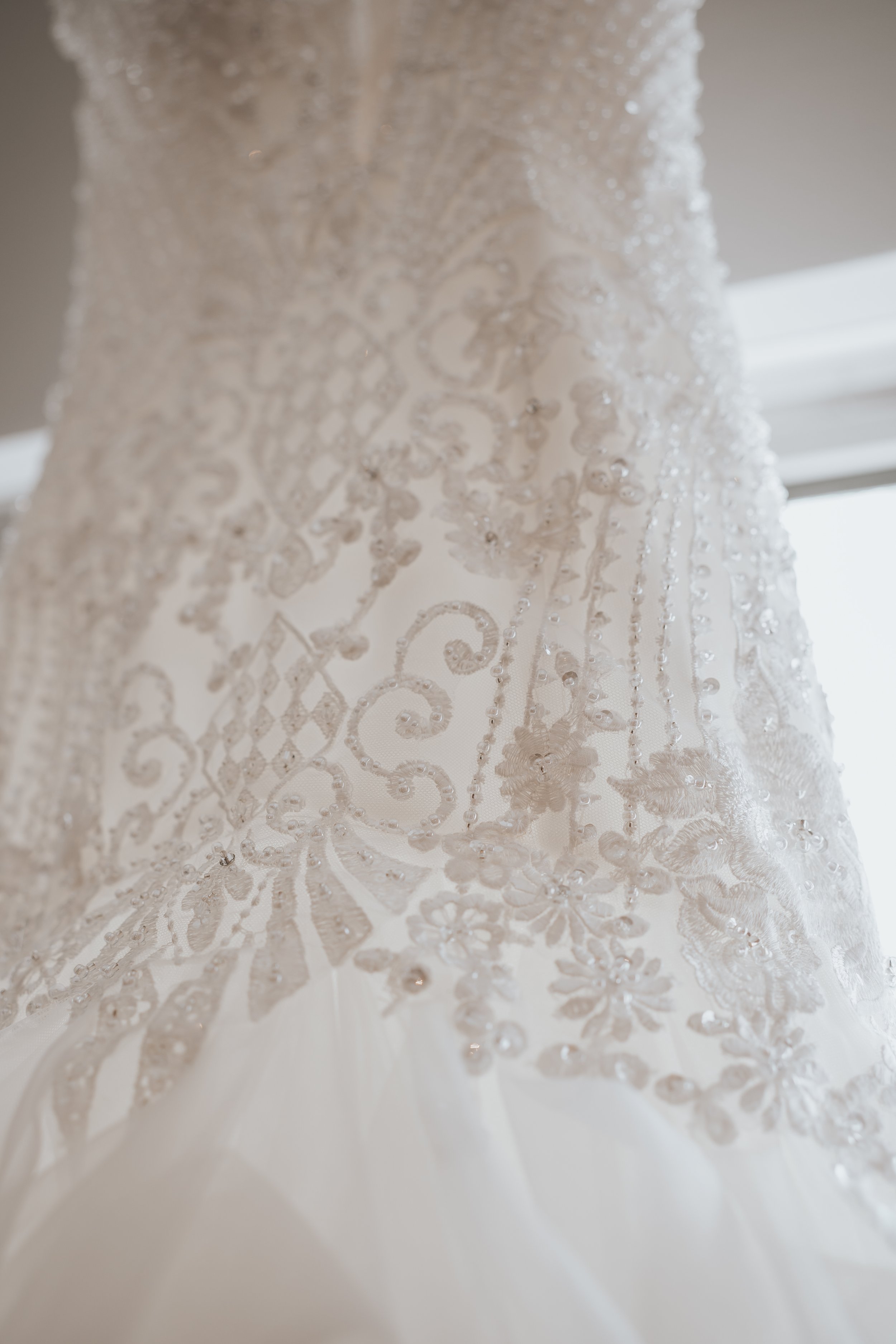 Close-up of lace and bead details on a white wedding dress.