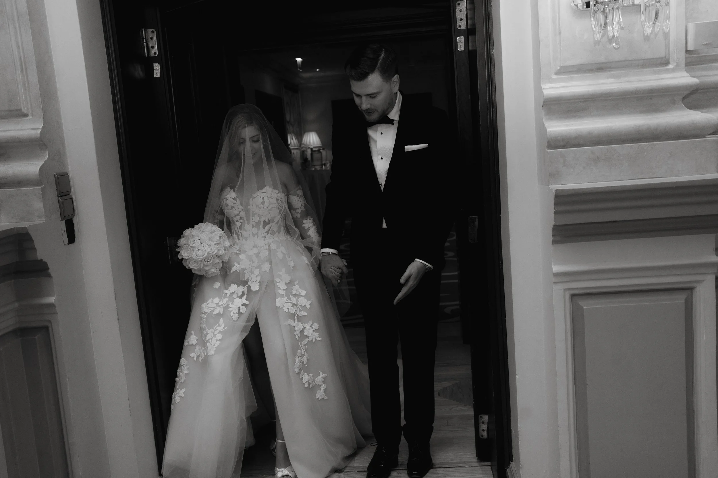 Bride and groom exiting doorway during wedding ceremony, black and white photo.