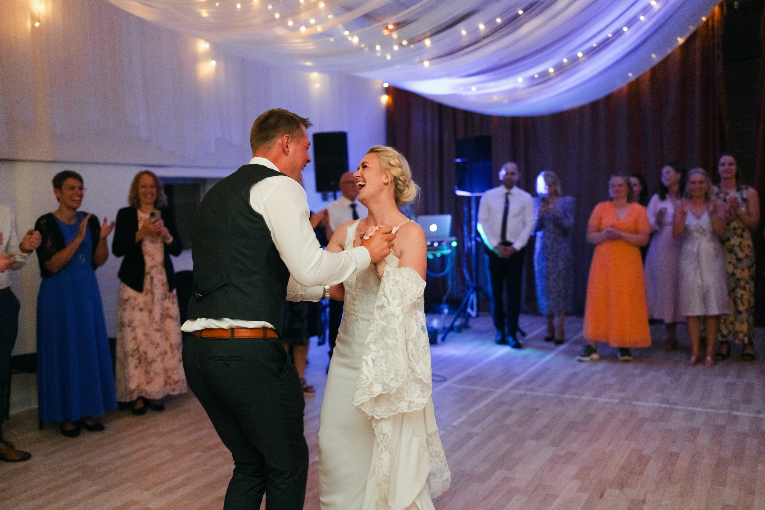 Bride and groom dancing at wedding reception with guests watching