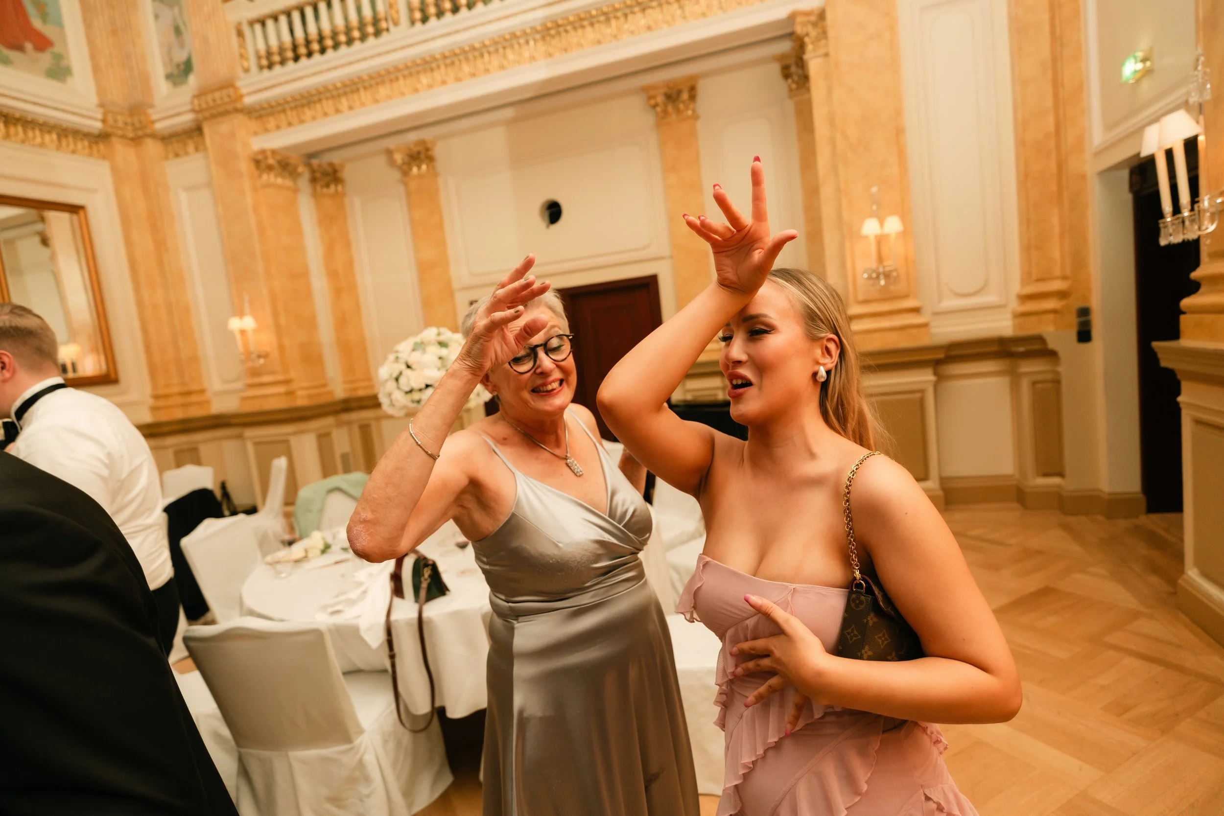 Two women dancing and having fun at an elegant indoor event.