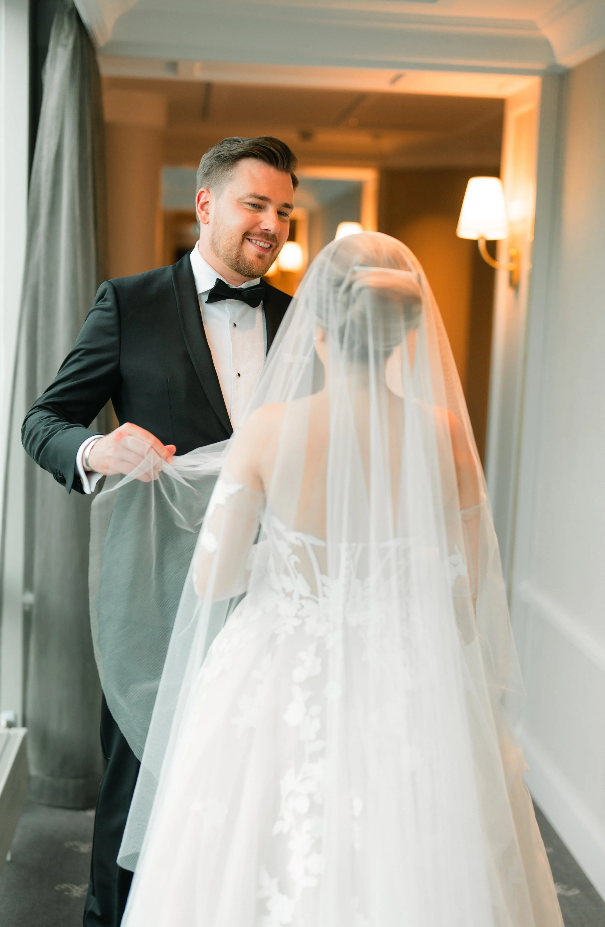 Bride and groom in formal attire sharing a moment indoors.