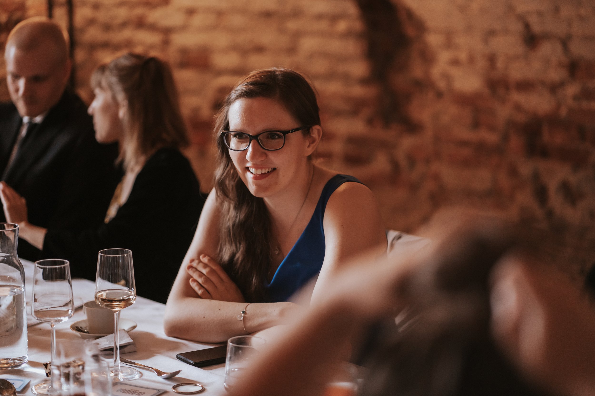 People sitting at a table in a cozy restaurant setting, talking and smiling.