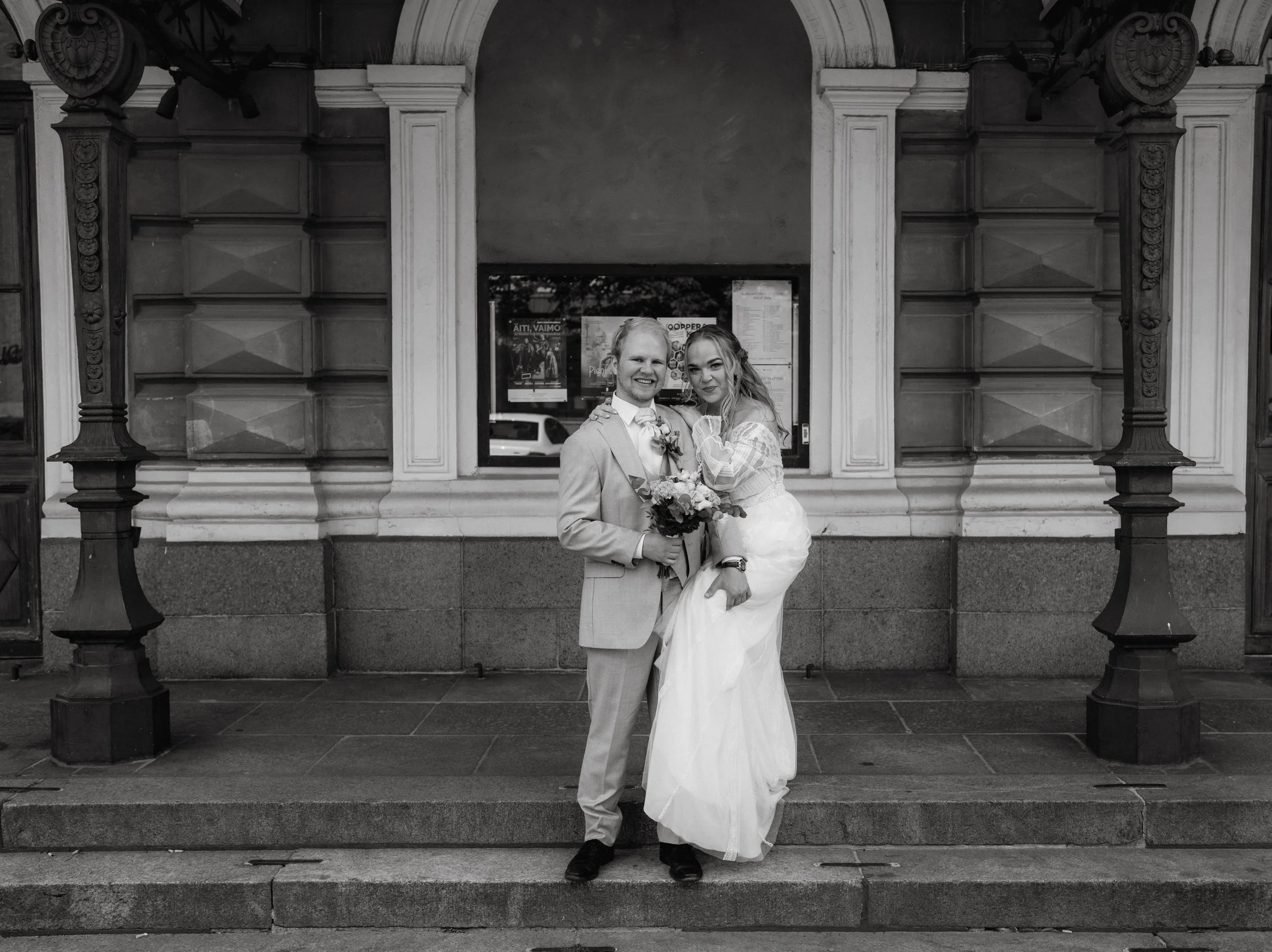 Black and white wedding photo of couple posing in front of building with columns.