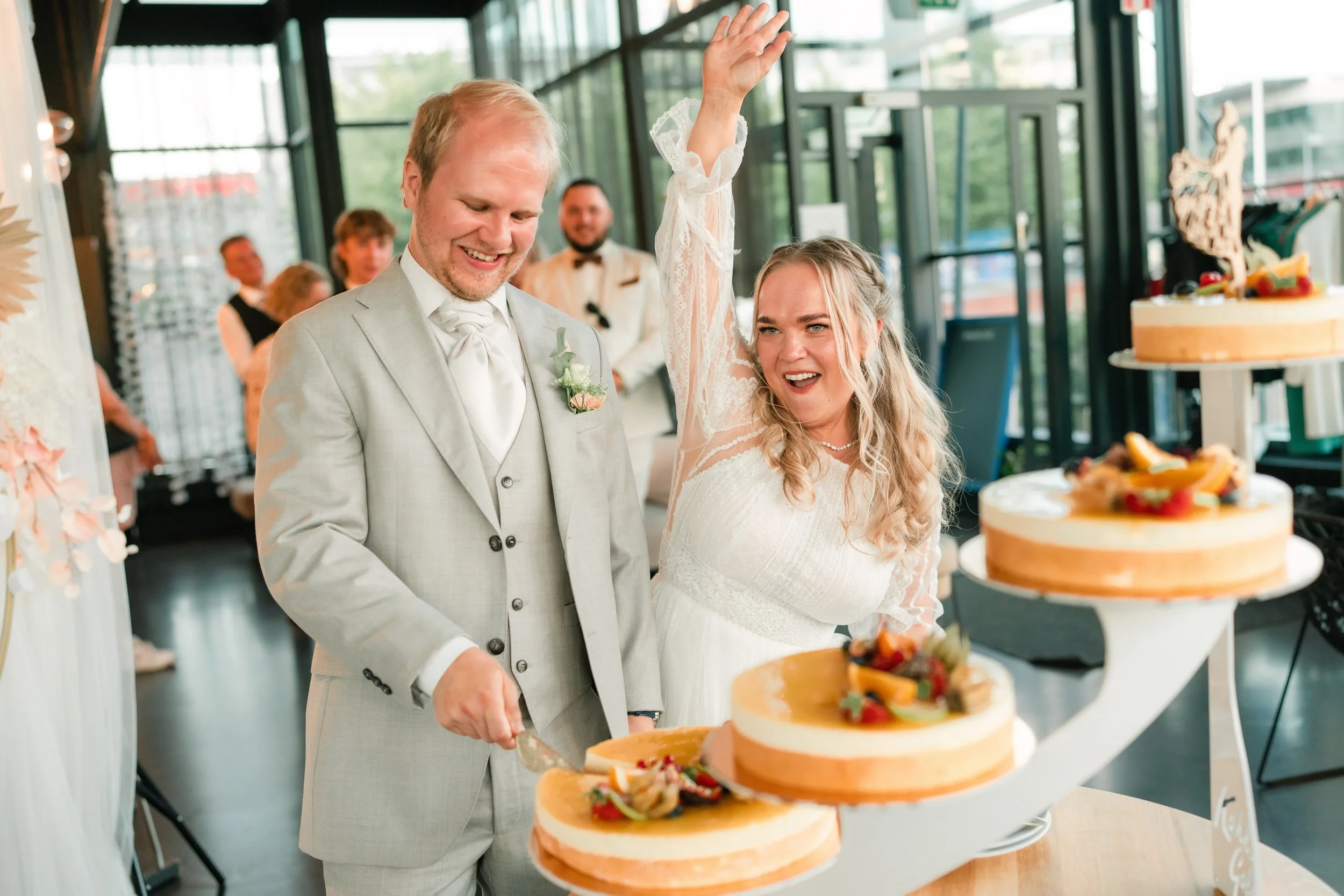Bride and groom cutting wedding cake, festive atmosphere.