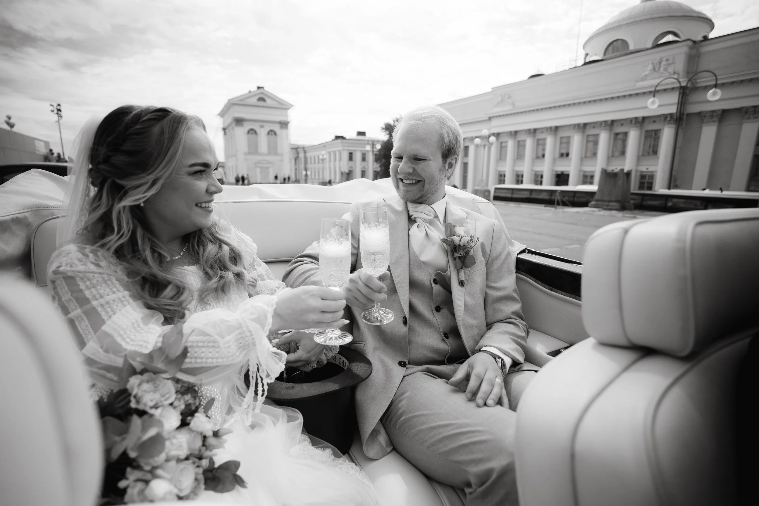 Bride and groom toasting with champagne in a car