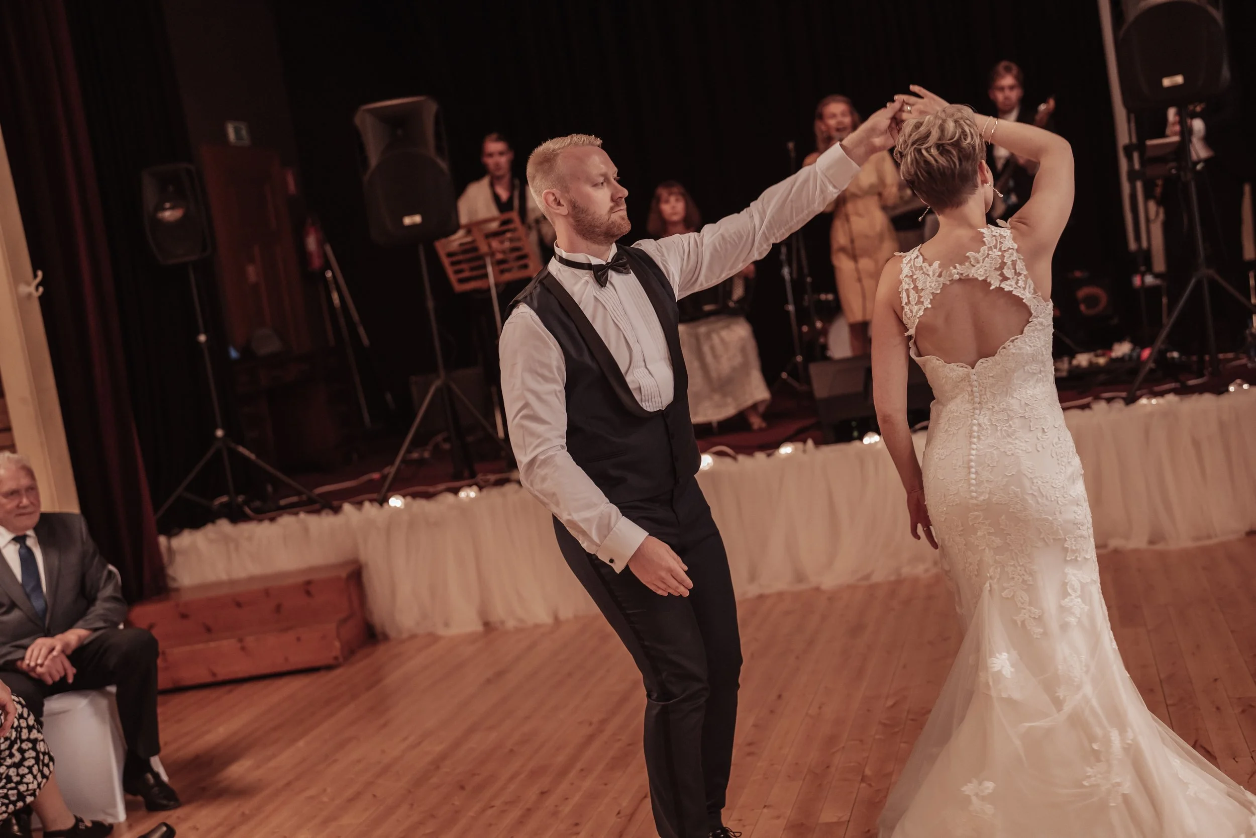 A couple dancing at a wedding reception with a band playing in the background.
