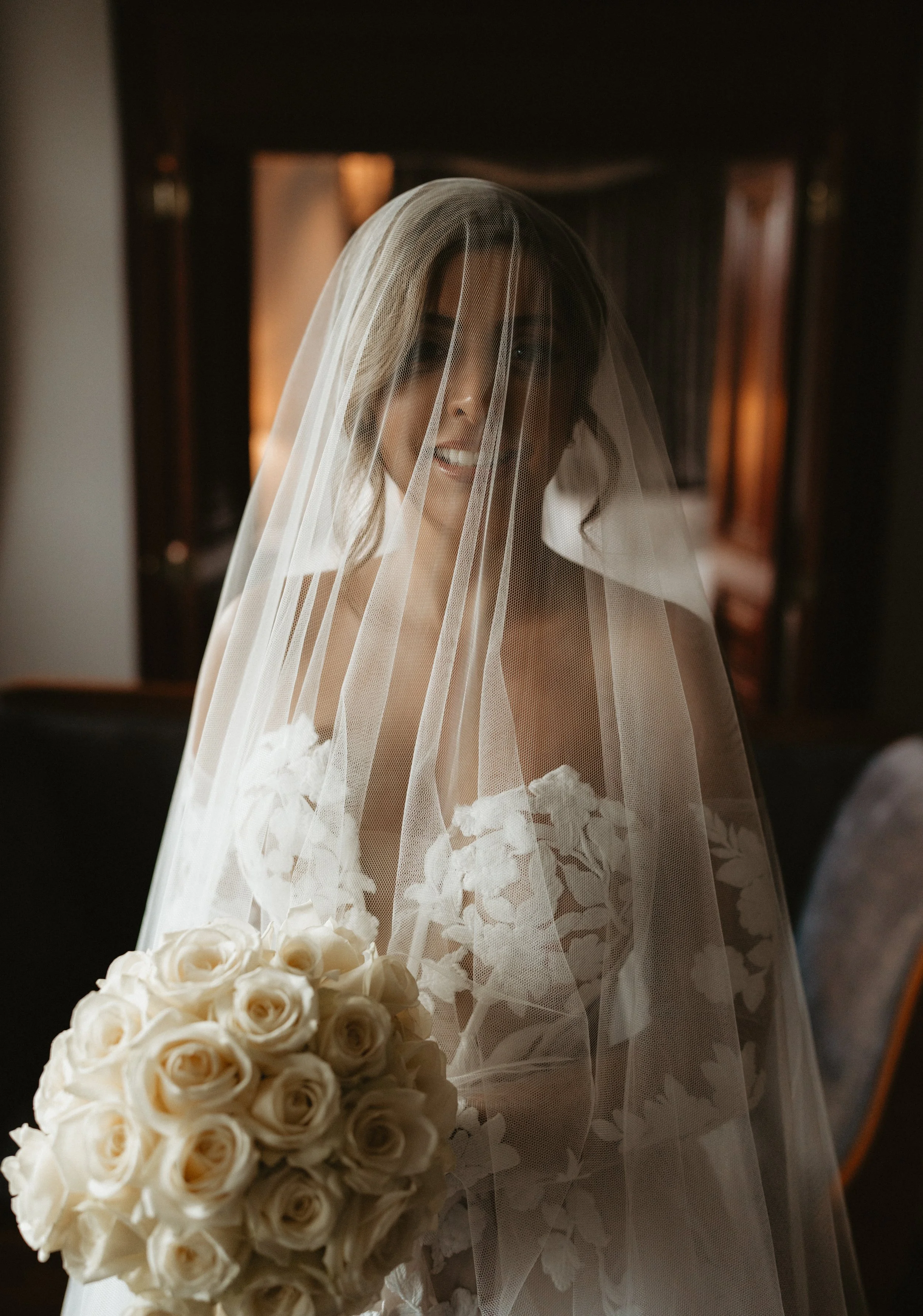 Bride with veil holding a bouquet of white roses