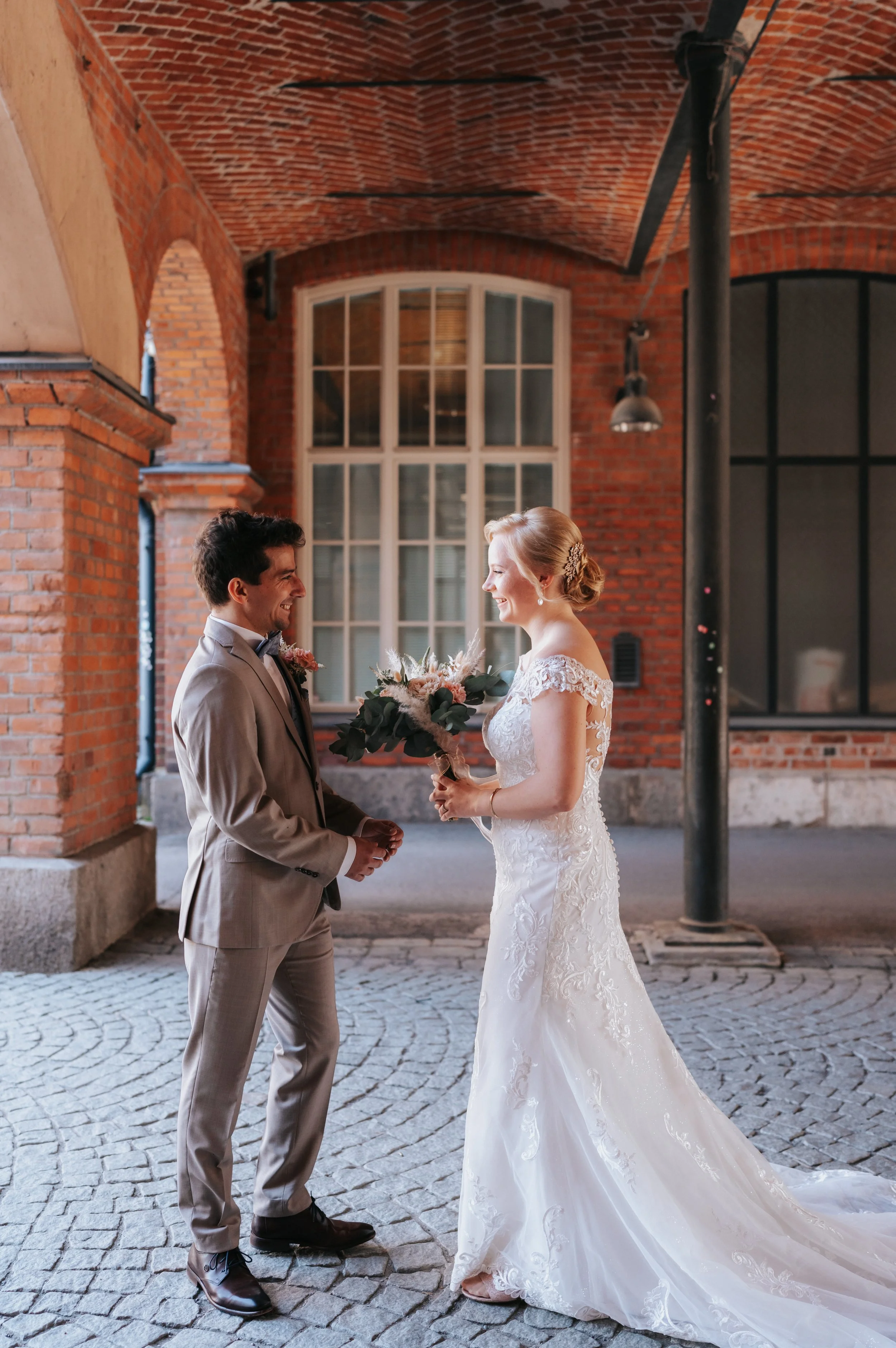 Bride and groom smiling indoors with brick walls
