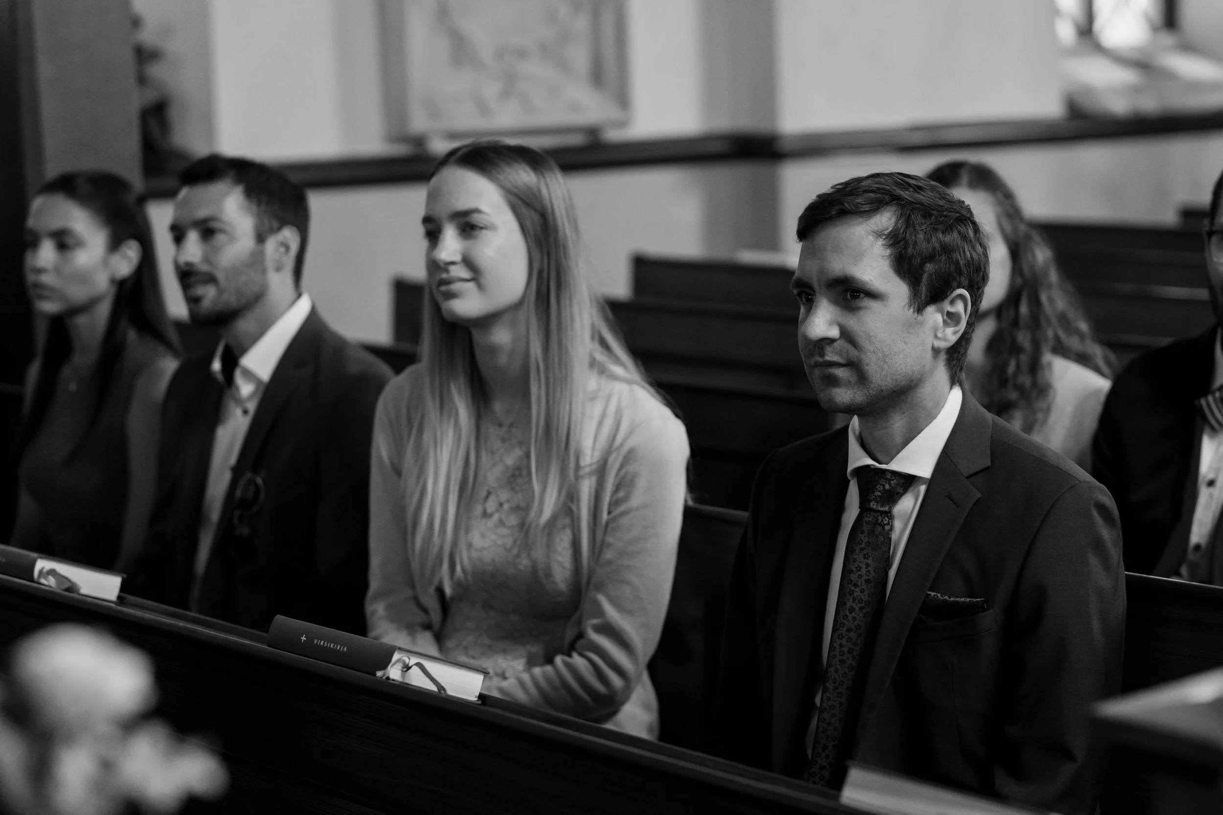 People sitting in a church pew, black and white photo.